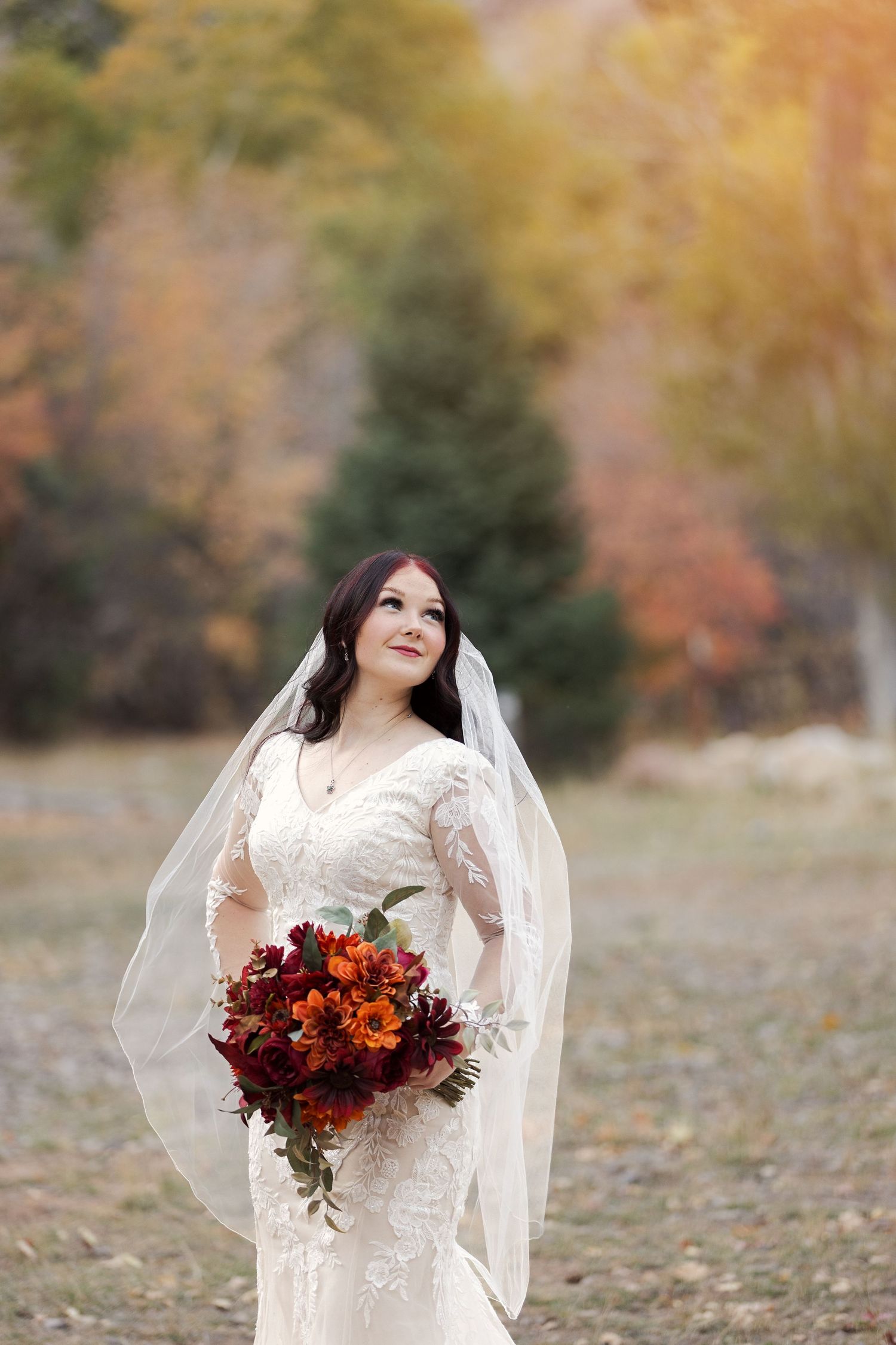 Autumn bridal portrait featuring lace dress and vibrant fall-colored bouquet.
