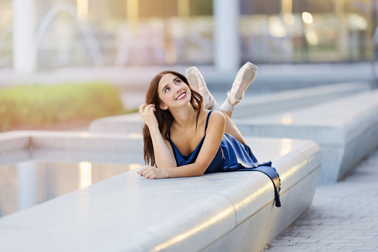 Woman in navy blue dress posing outdoors on stone steps during golden hour lighting.