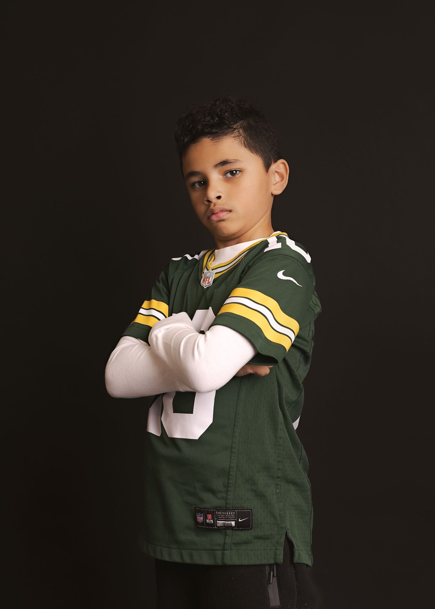 A young person wearing a Green Bay Packers jersey poses against a dark background in a series of photos.