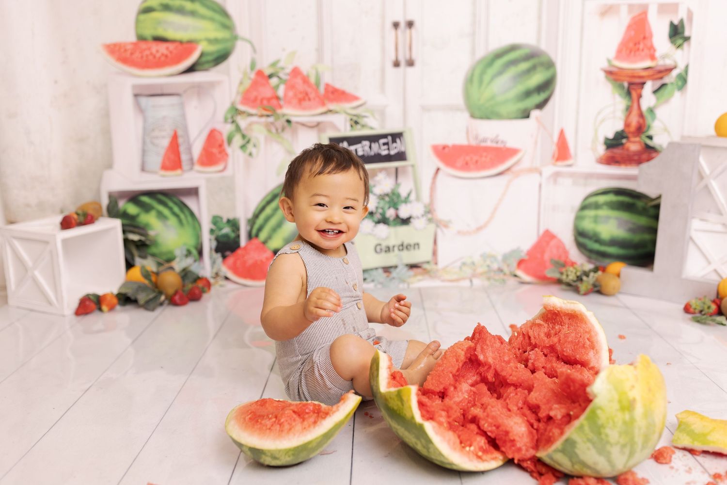 Fresh watermelon slices arranged in a summer-themed studio setting on white floor with fruit decorations.