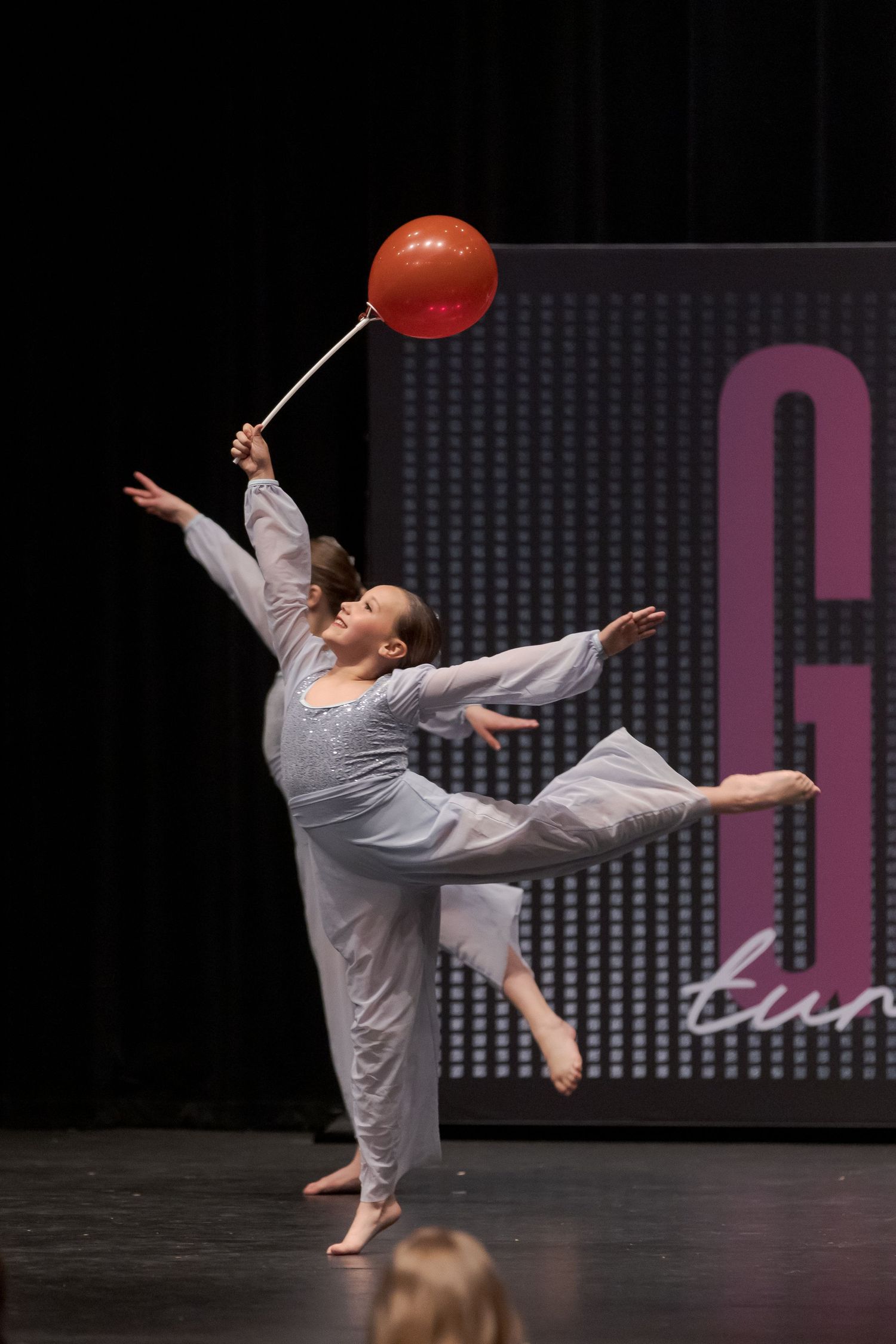 A series of dynamic dance poses showing a performer in a grey outfit executing high-energy movements on stage.