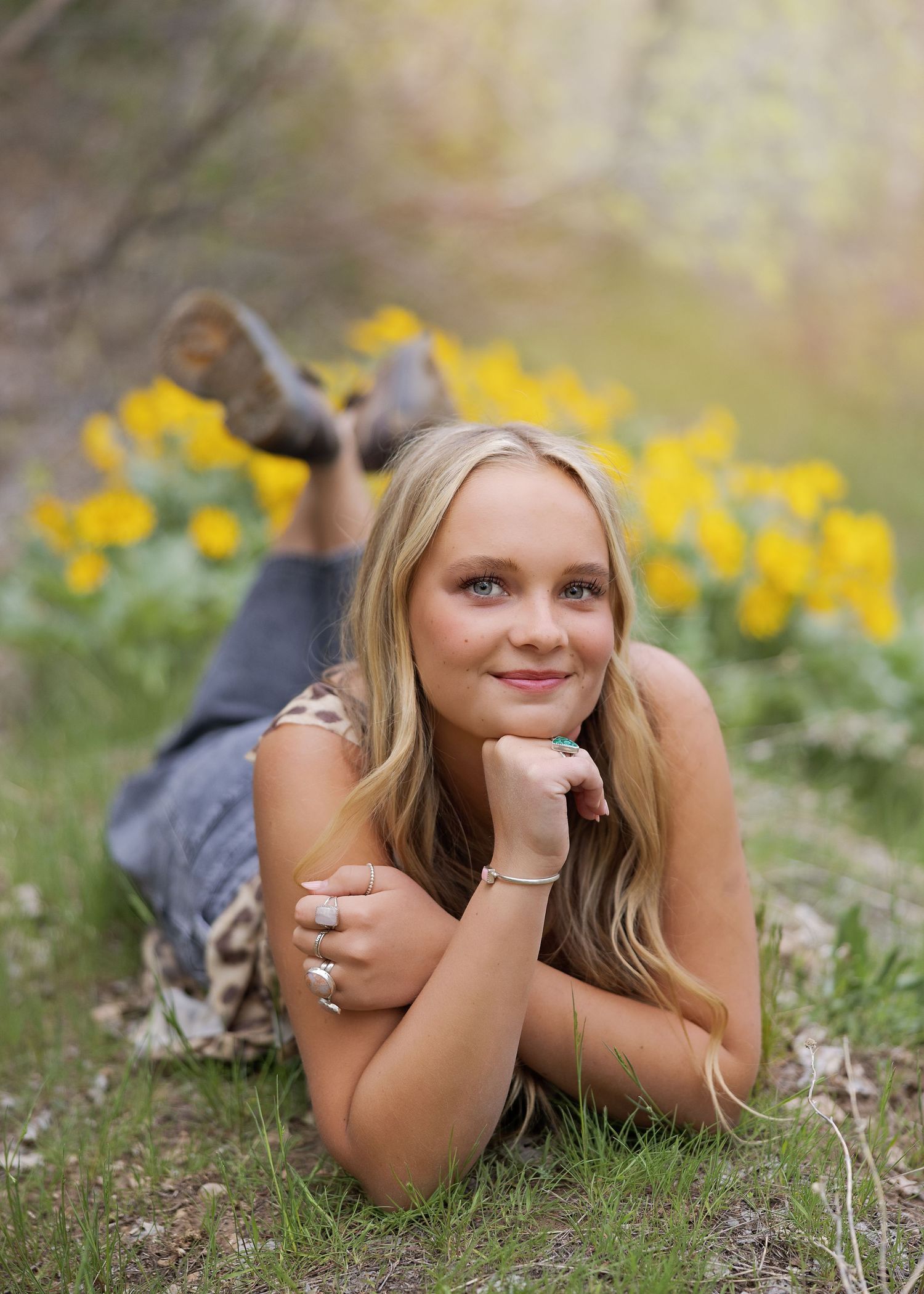 A person lies on grass near blooming yellow daffodils during a spring outdoor portrait session.
