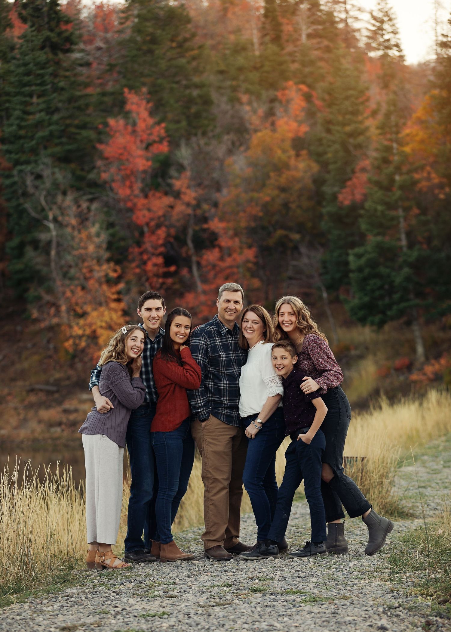 A group stands together on a mountain trail with vibrant fall colors and evergreen trees behind them.
