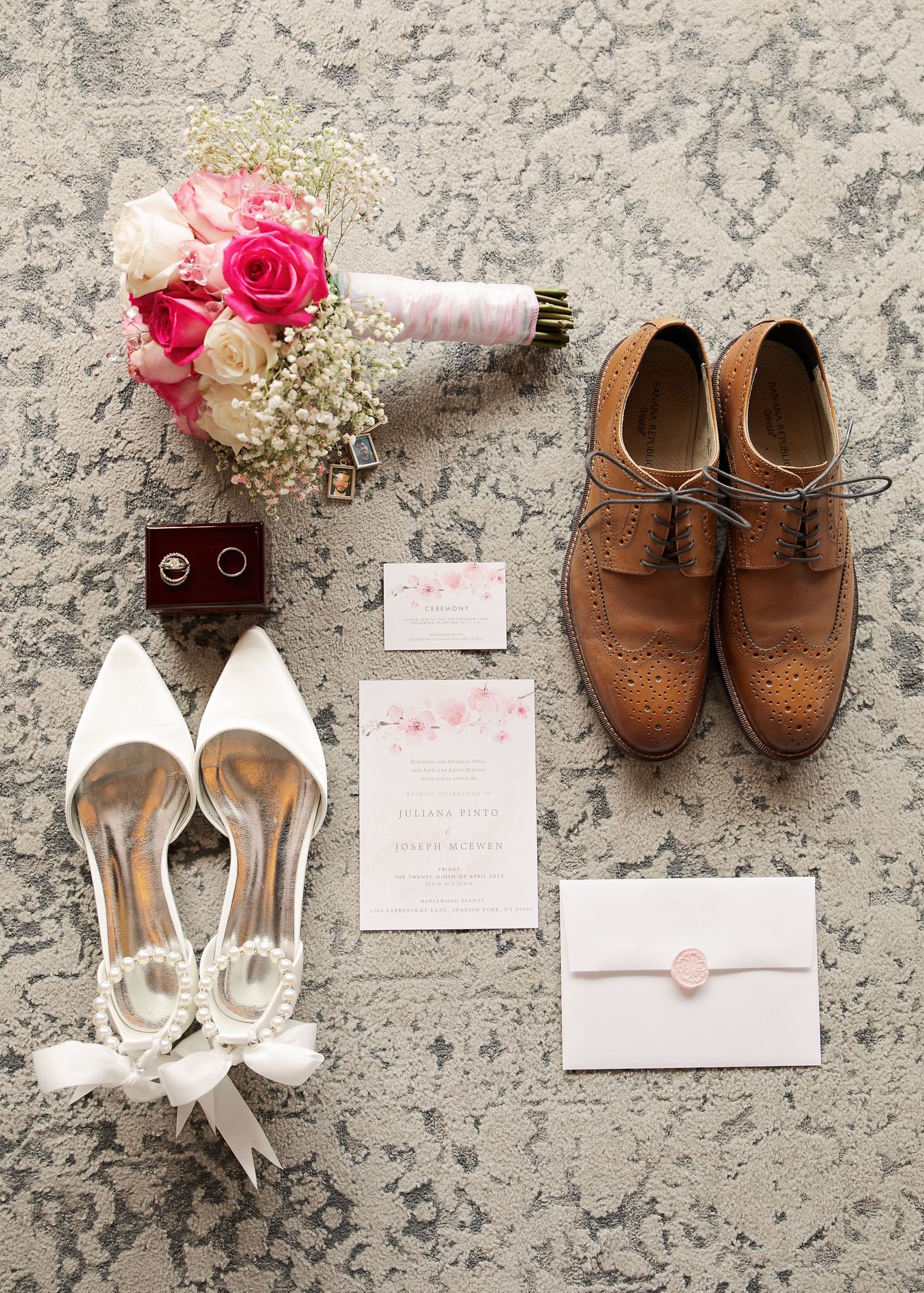 Wedding flat lay featuring pink bouquet, bridal shoes, invitation suite and groom's brown oxfords.
