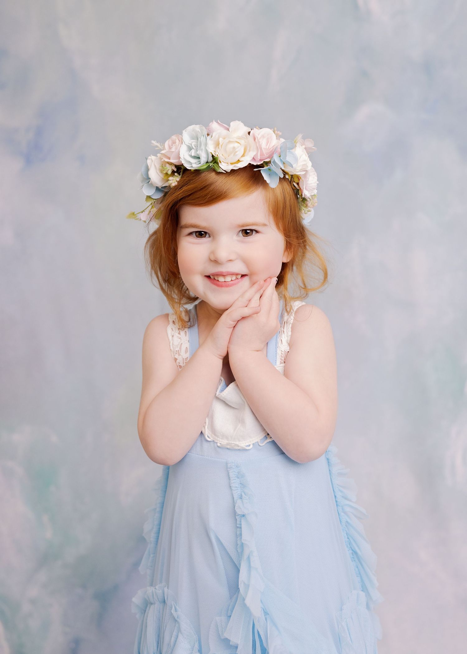 Sweet portrait in blue dress and floral crown against dreamy painted background.