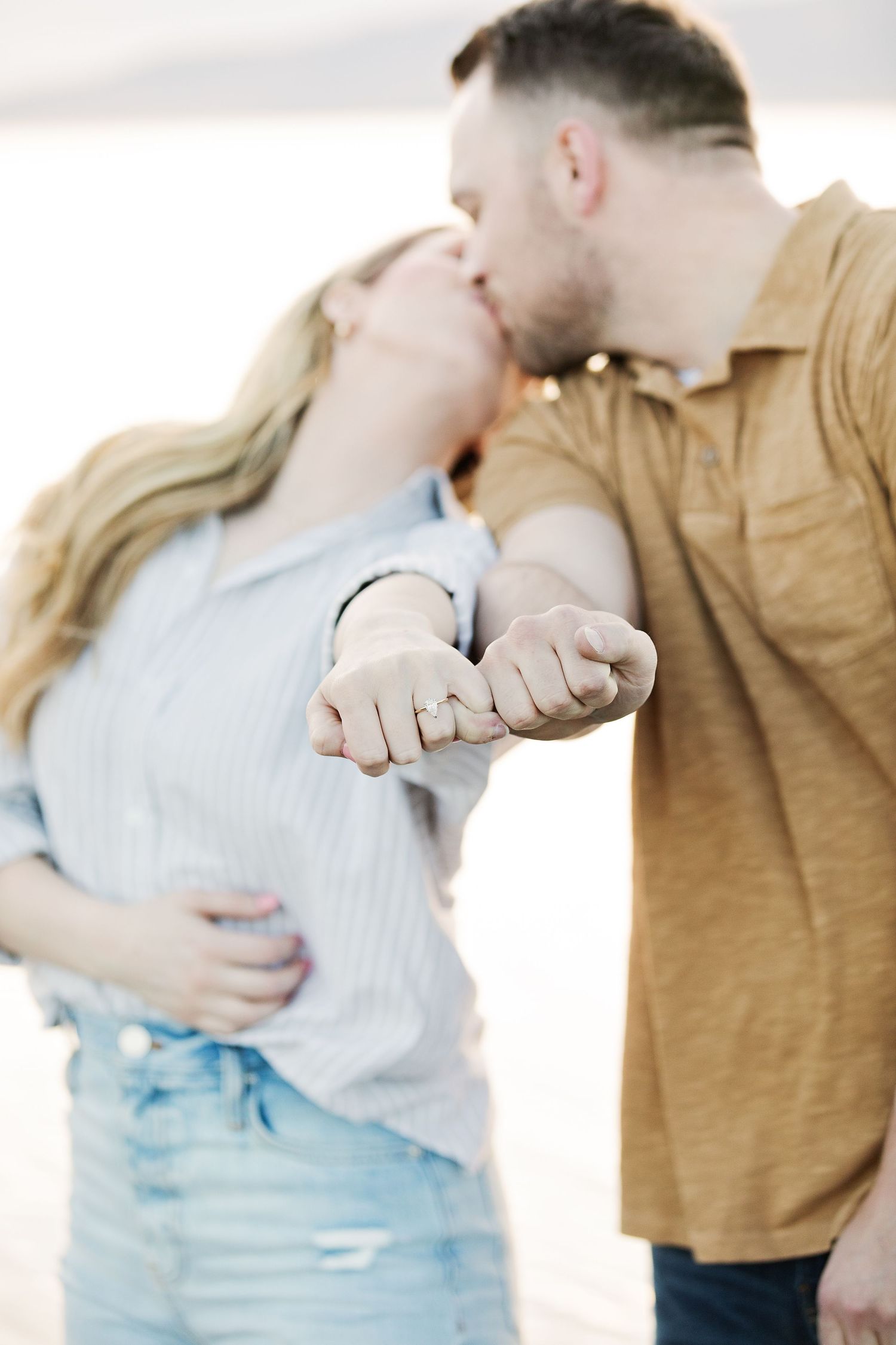 A romantic couple sharing an intimate moment while showing their intertwined hands in casual attire.