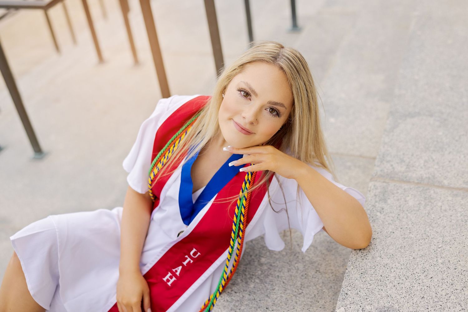Graduate in academic regalia smiling and posing for graduation photos outdoors.