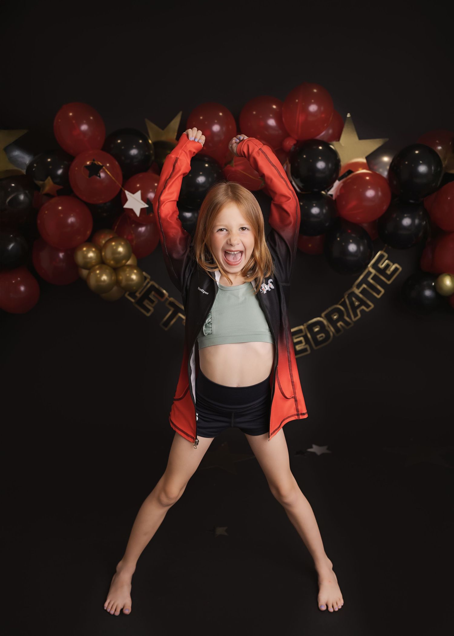 Gymnastic sequence of someone in red shirt performing dynamic floor movements against black backdrop with red and gold balloons.