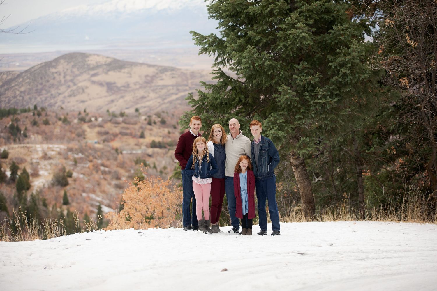 Group portrait on snowy hillside with mountain vista in background.