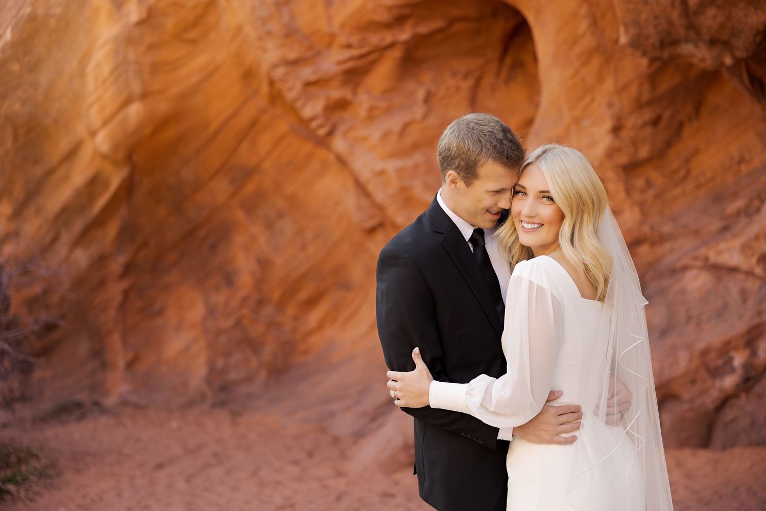Romantic embrace captured against majestic red rock canyon walls.
