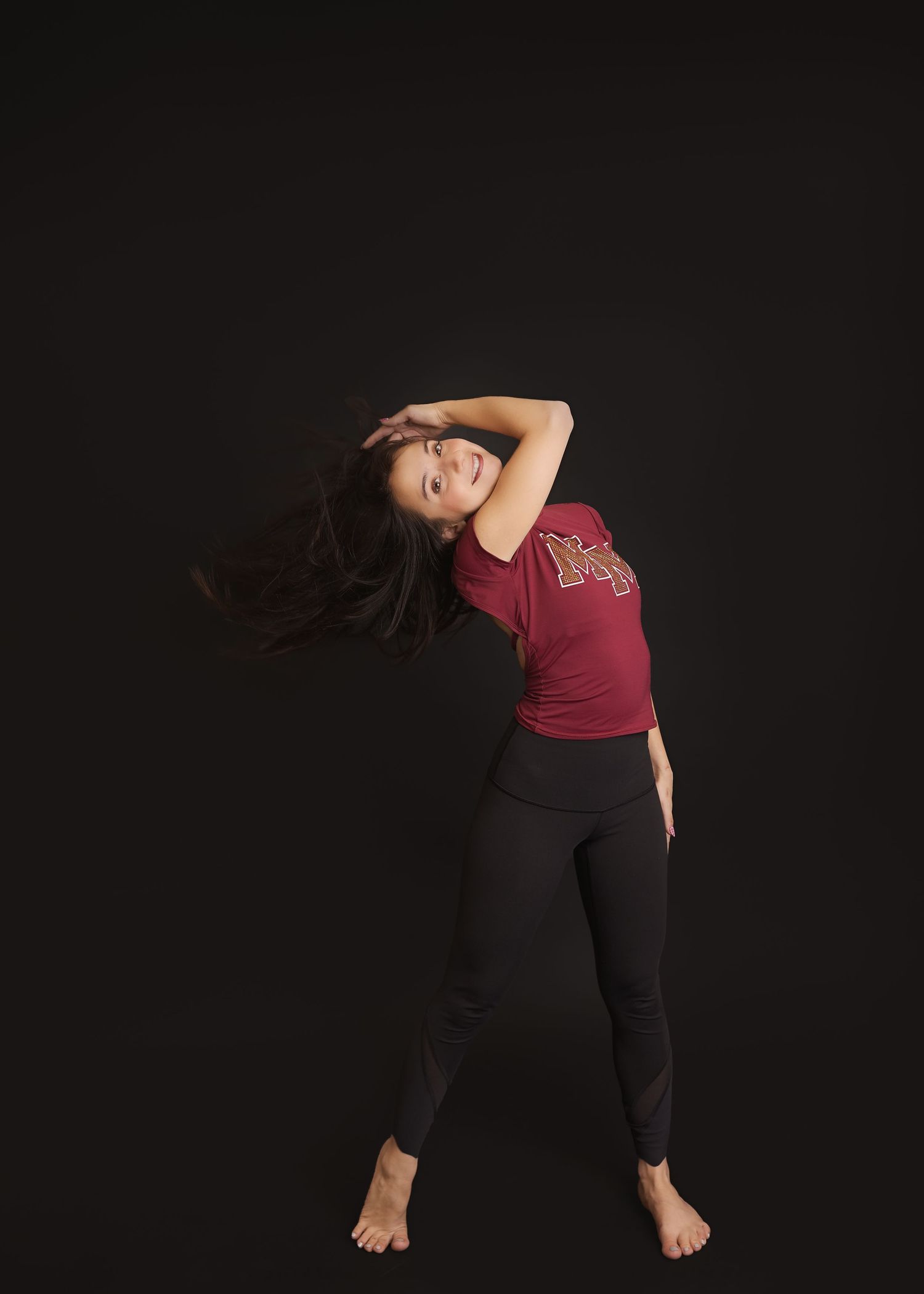 A dancer in black pants performs fluid movements against a dark background, creating an artistic silhouette effect.