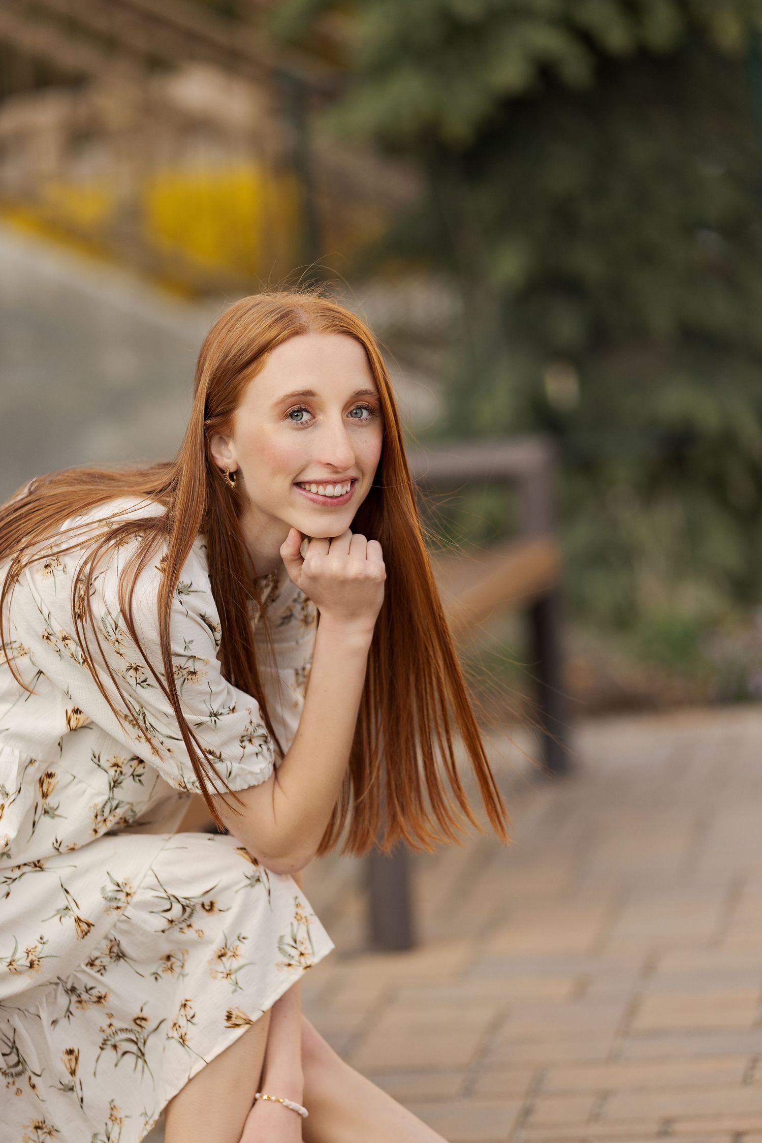 Portrait of person in floral dress sitting outdoors in casual pose.