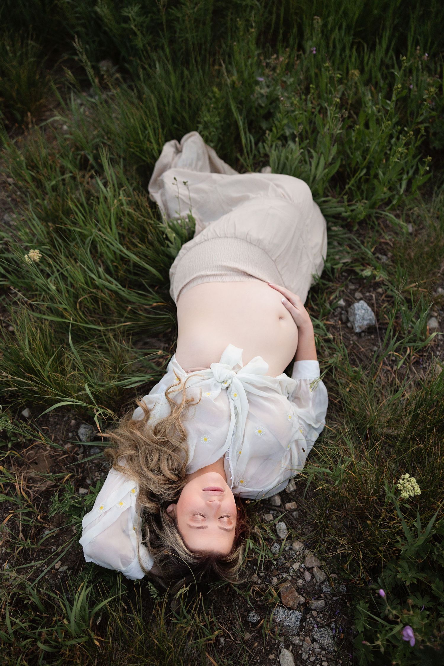 A collection of soft, ethereal photos showing someone lying peacefully in tall grass wearing vintage white clothing.