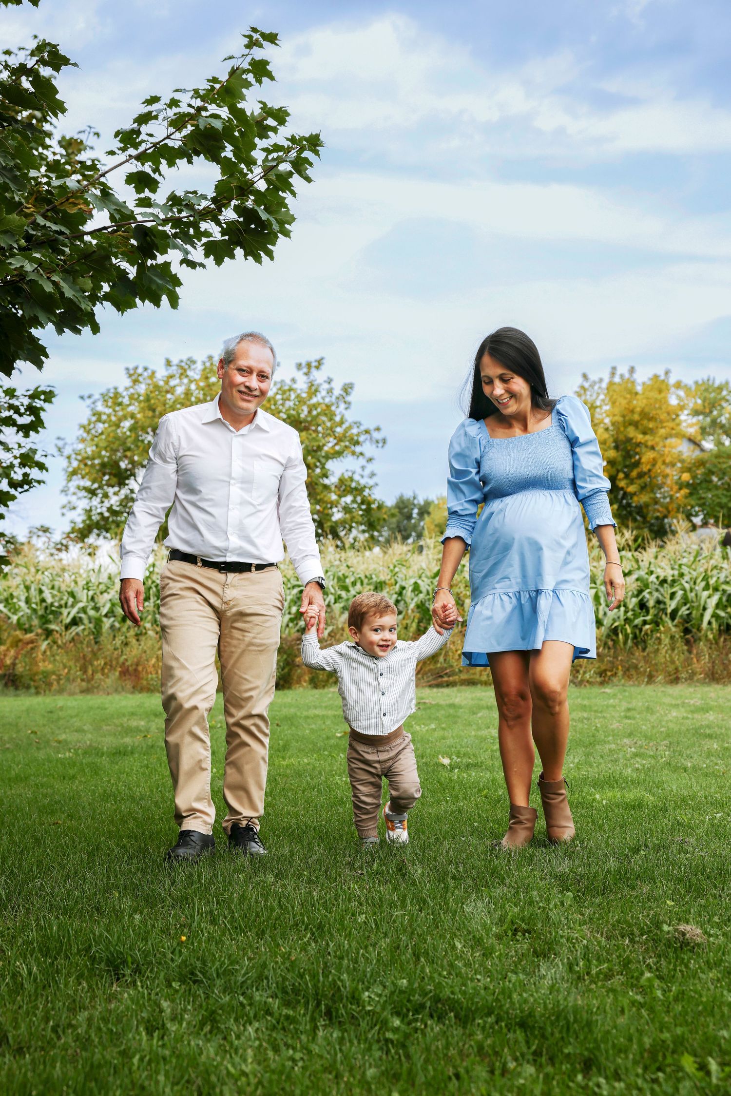 Three people walking together through a grassy meadow on a sunny summer day.