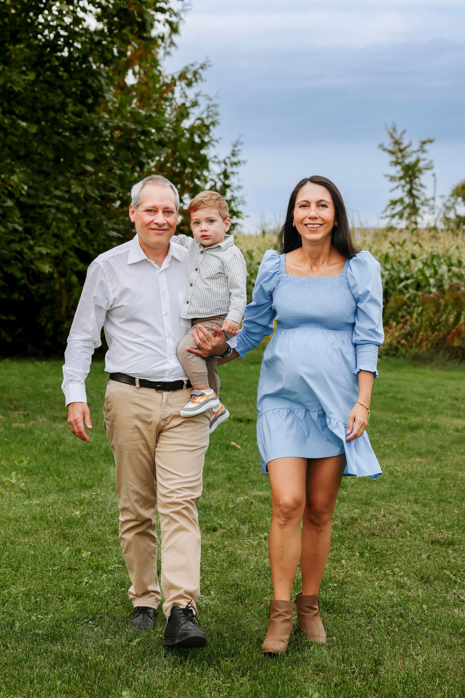 Family members walking together and playing on a grassy hill during an outdoor photo session.