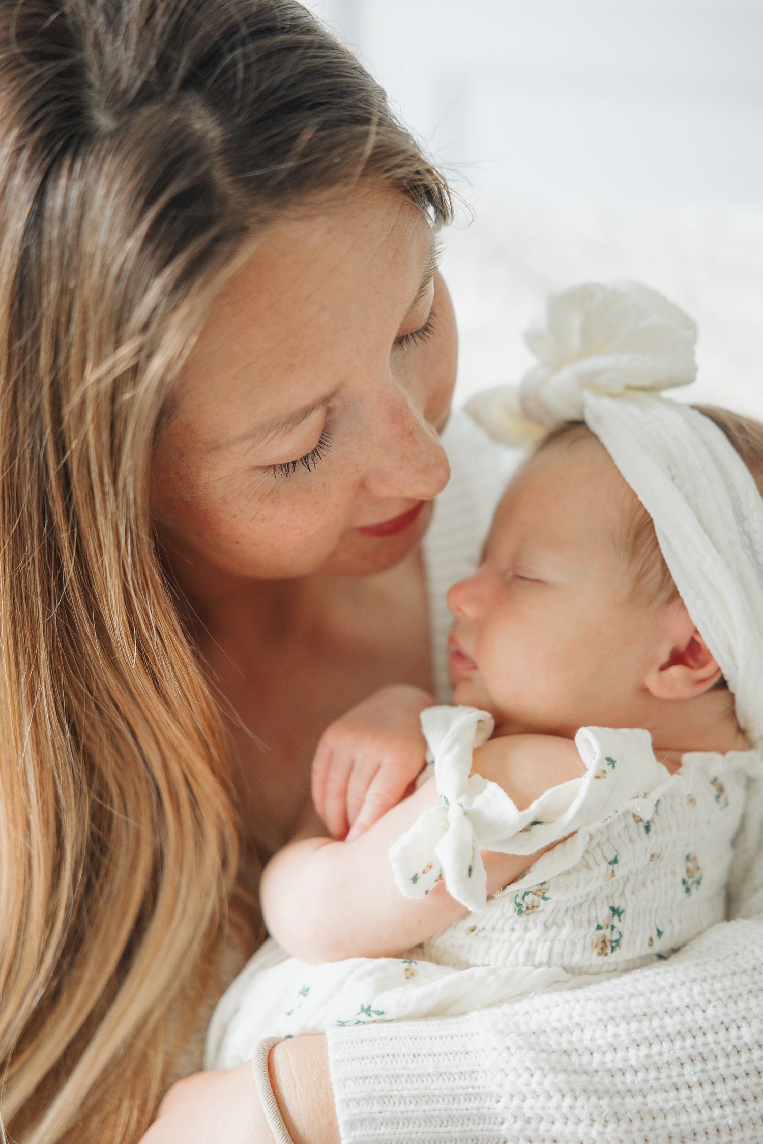 Maman tenant son nouveau-né dans ses bras lors d’une séance photo lifestyle naturelle. / Mom holding her newborn baby during a natural lifes