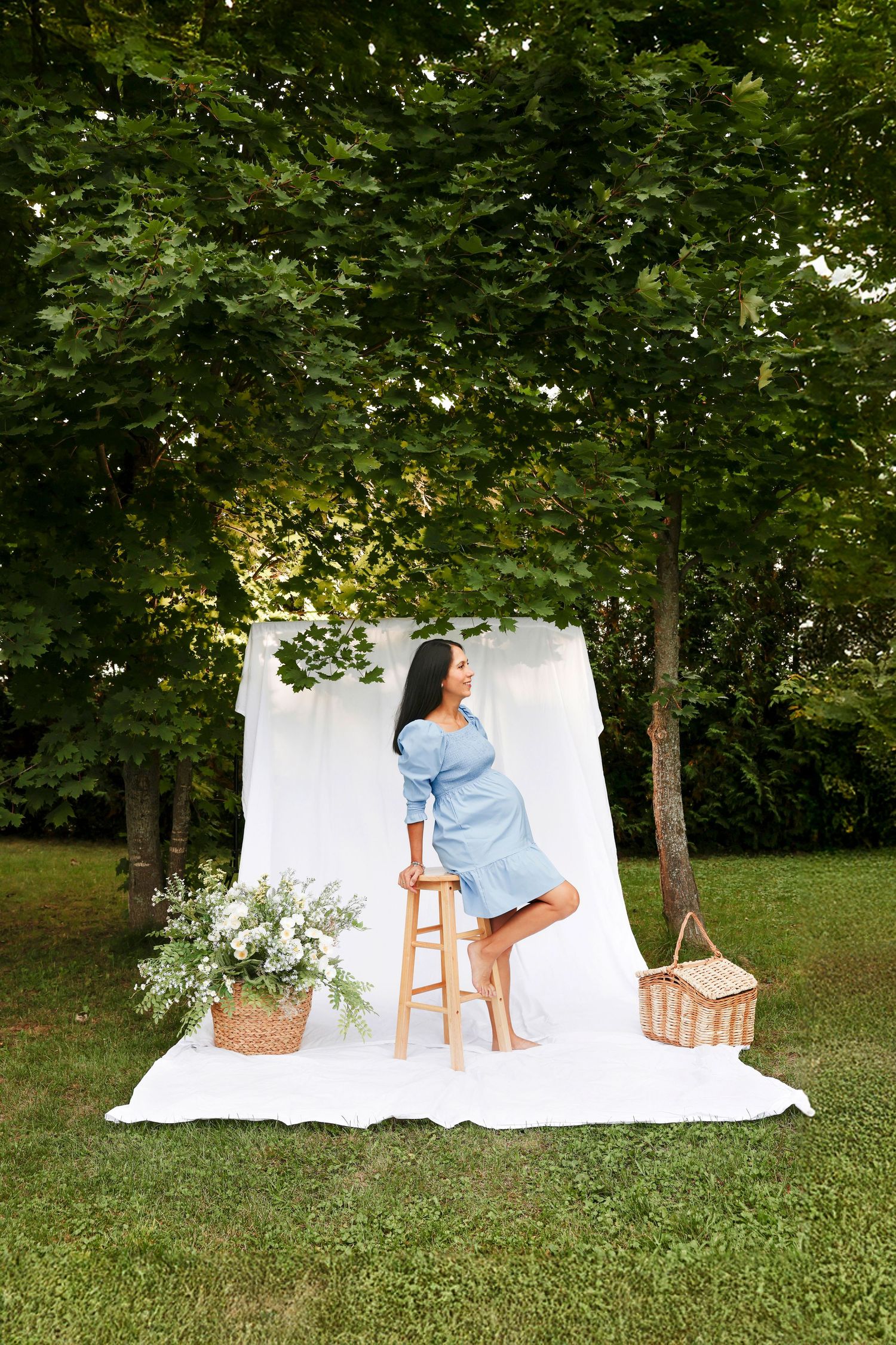 White backdrop setup in a grassy outdoor setting with trees and props for a photography session.