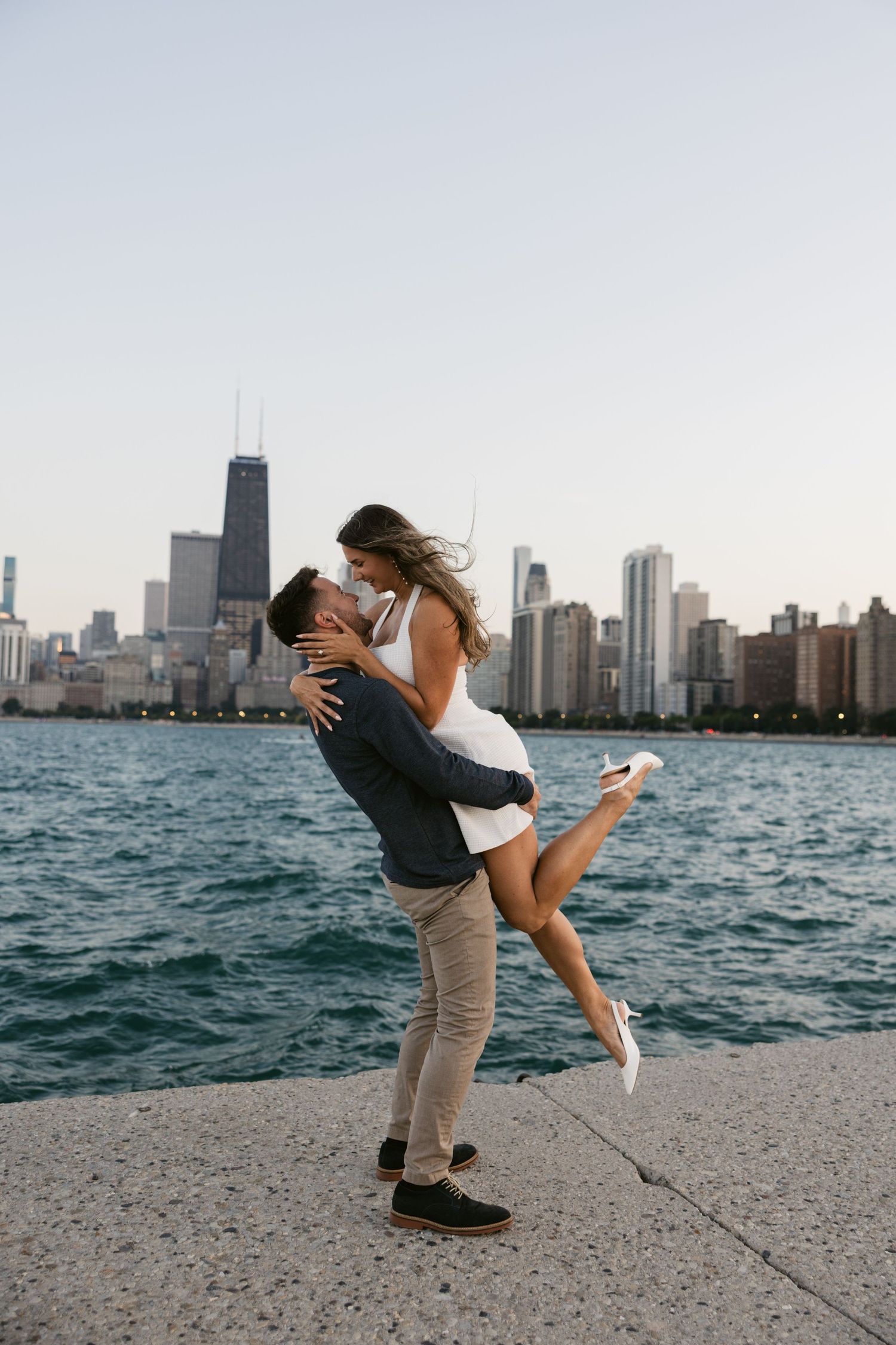 Couple embraces while enjoying sunset at North Avenue Beach with Chicago skyline view.
