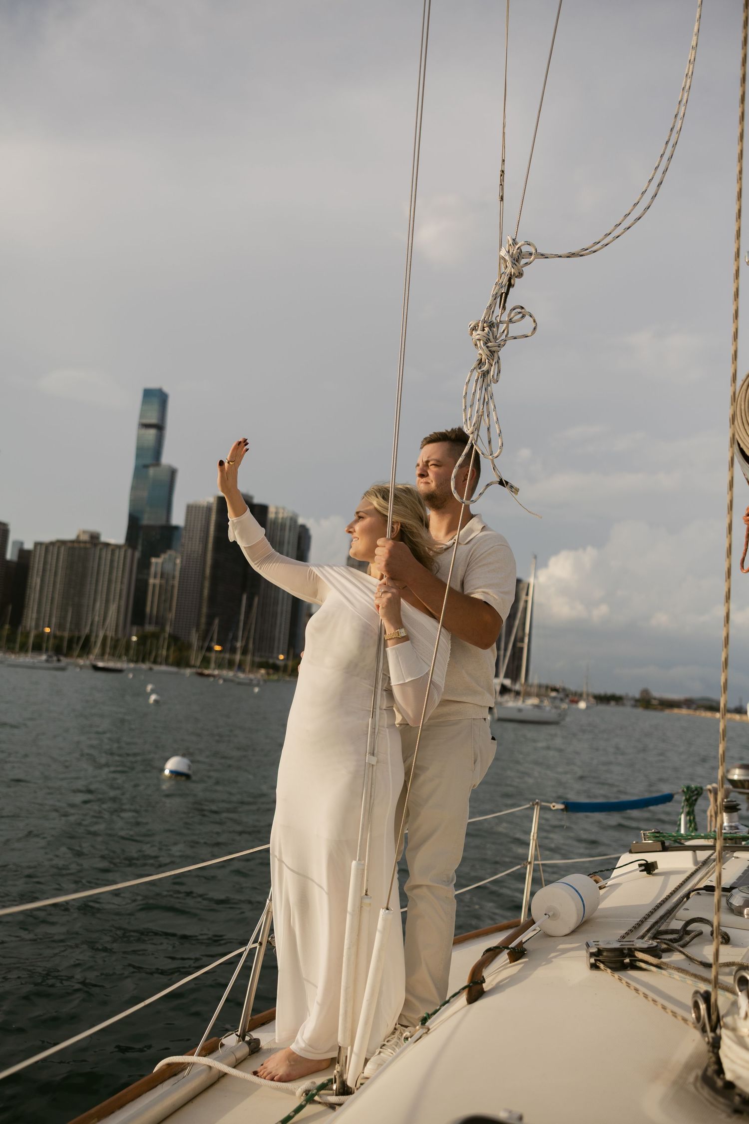 A couple in white outfits enjoying a romantic moment on a sailboat with the Chicago skyline in the background.