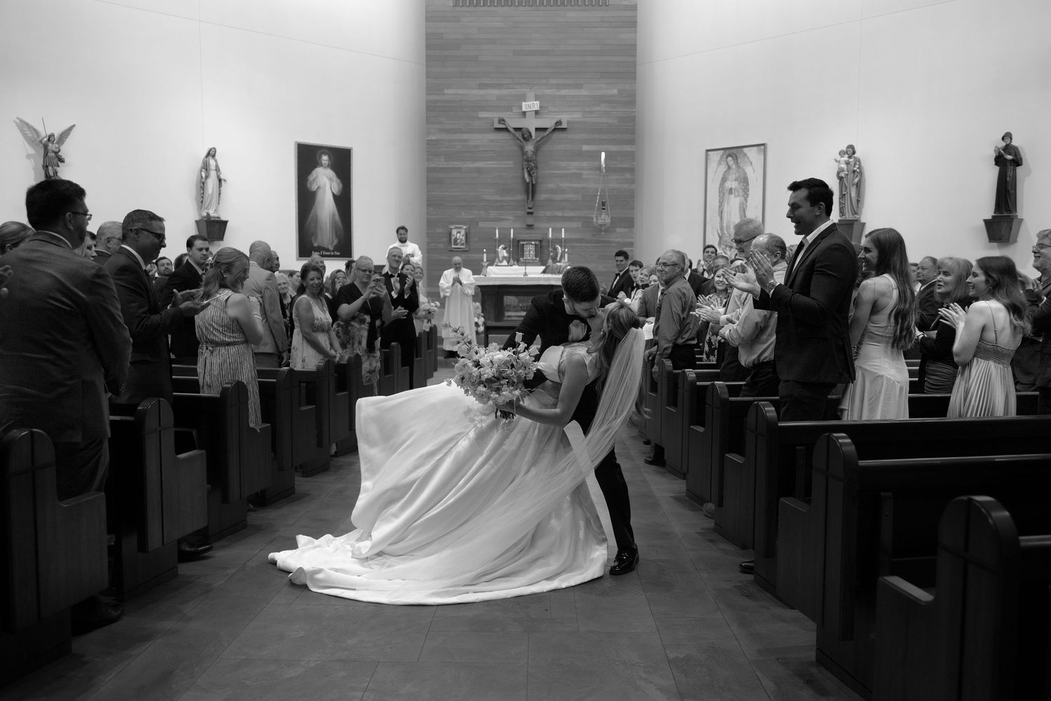A couple shares a tender moment in a church during a wedding ceremony while guests look on from the pews.