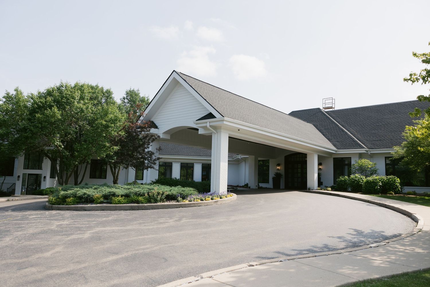 Exterior view of a white modern church building complex with parking area.