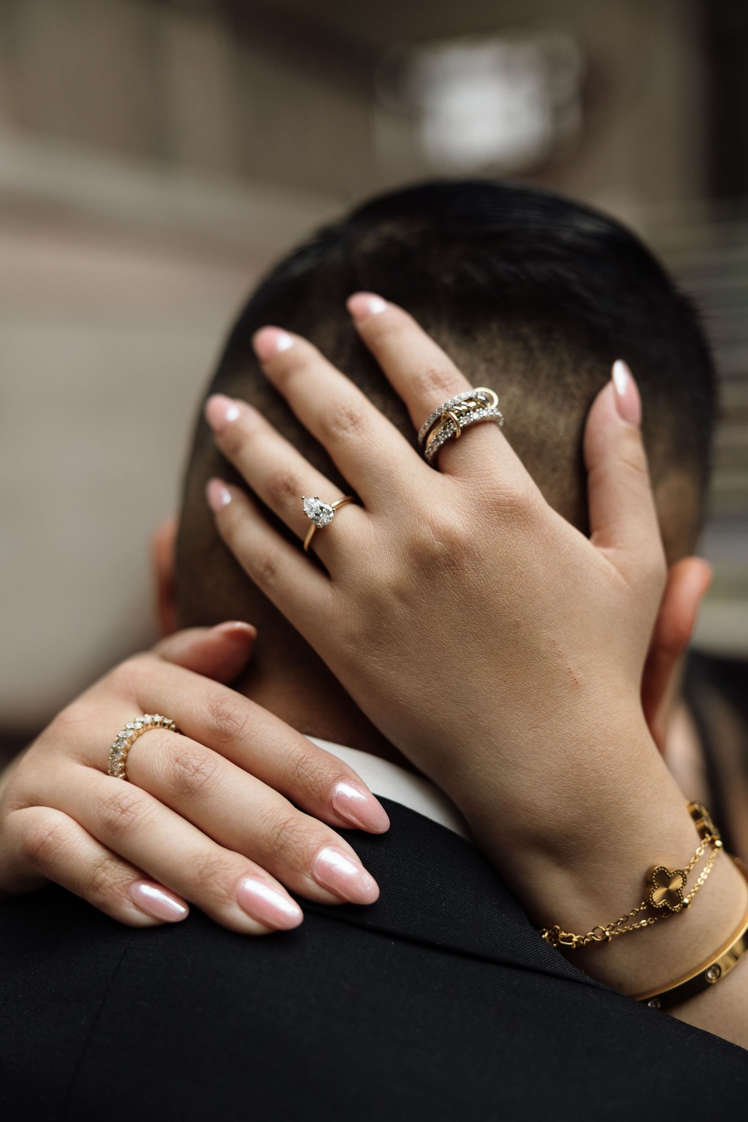 Close-up of hands wearing elegant rings and jewelry against a dark background.
