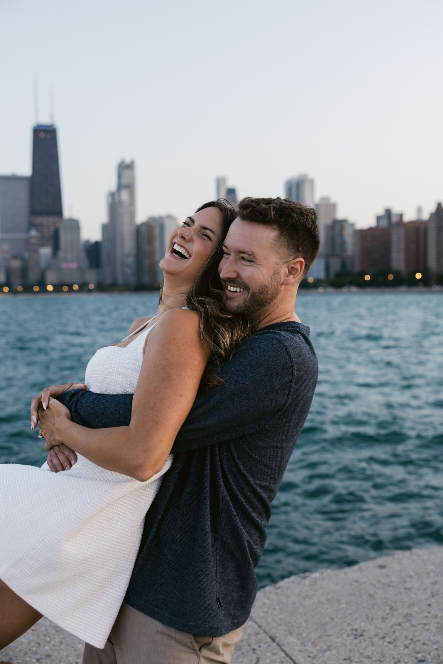 A joyful couple laughs together during their lakefront photoshoot in Chicago.