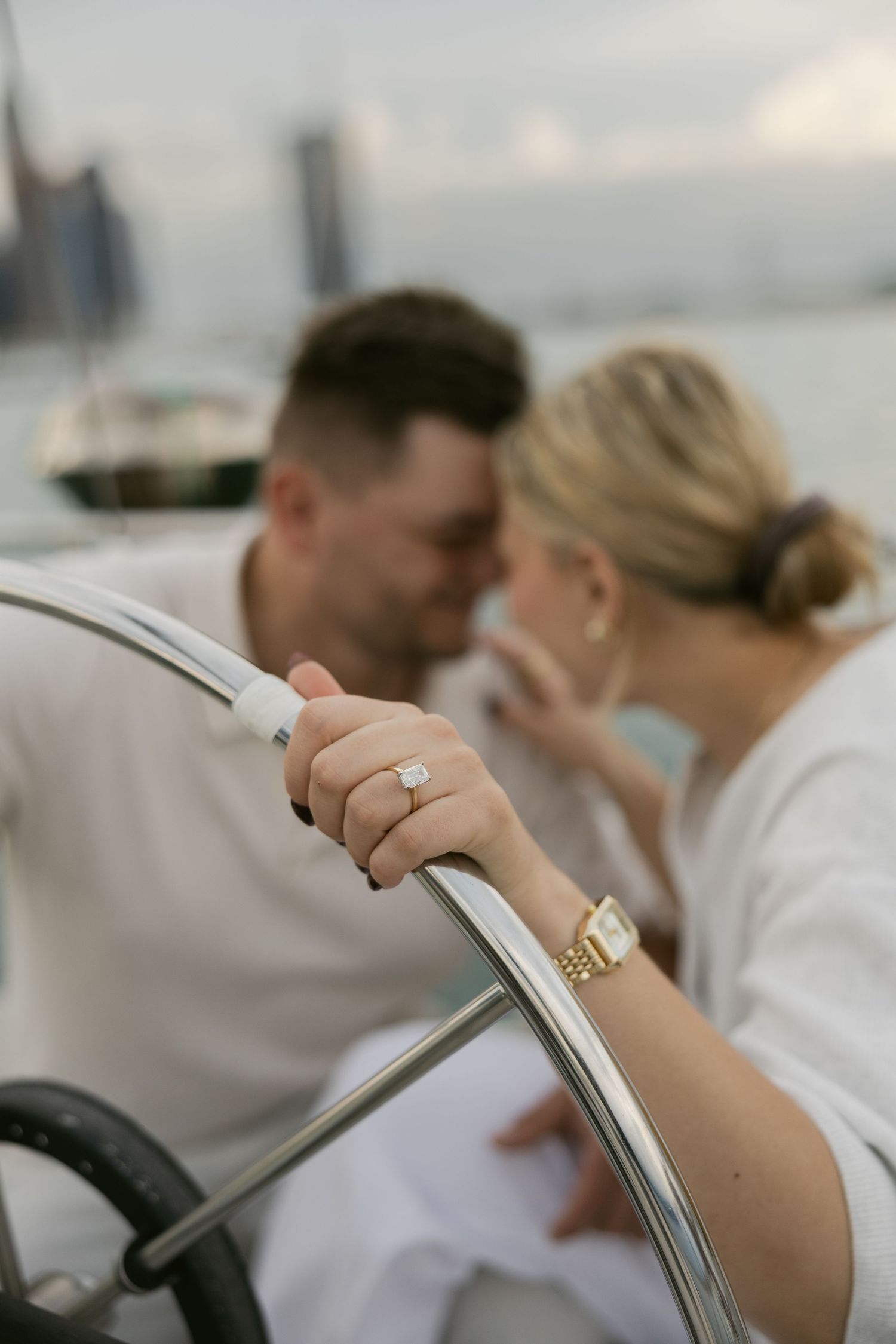 Close-up view of hands and rings on a boat railing during a nautical photoshoot.