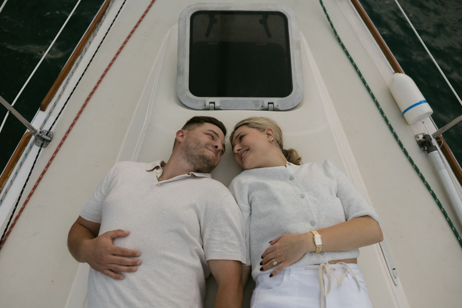 Romantic couple relaxing together on the deck of a sailboat during a golden hour cruise.