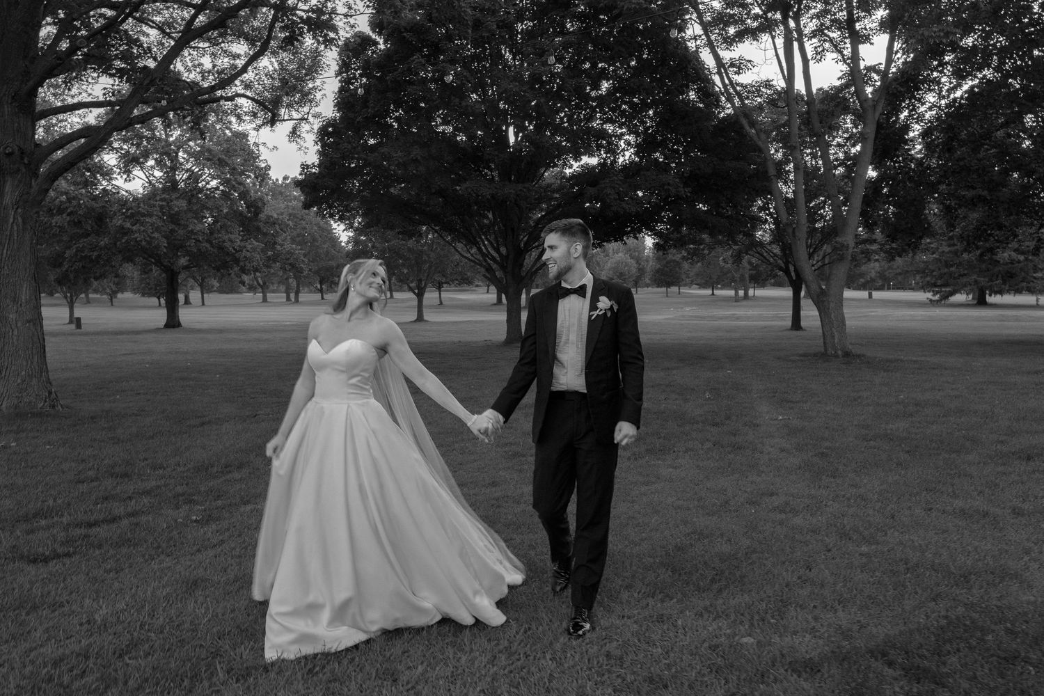 A couple enjoying a romantic walk through a scenic park on their wedding day.