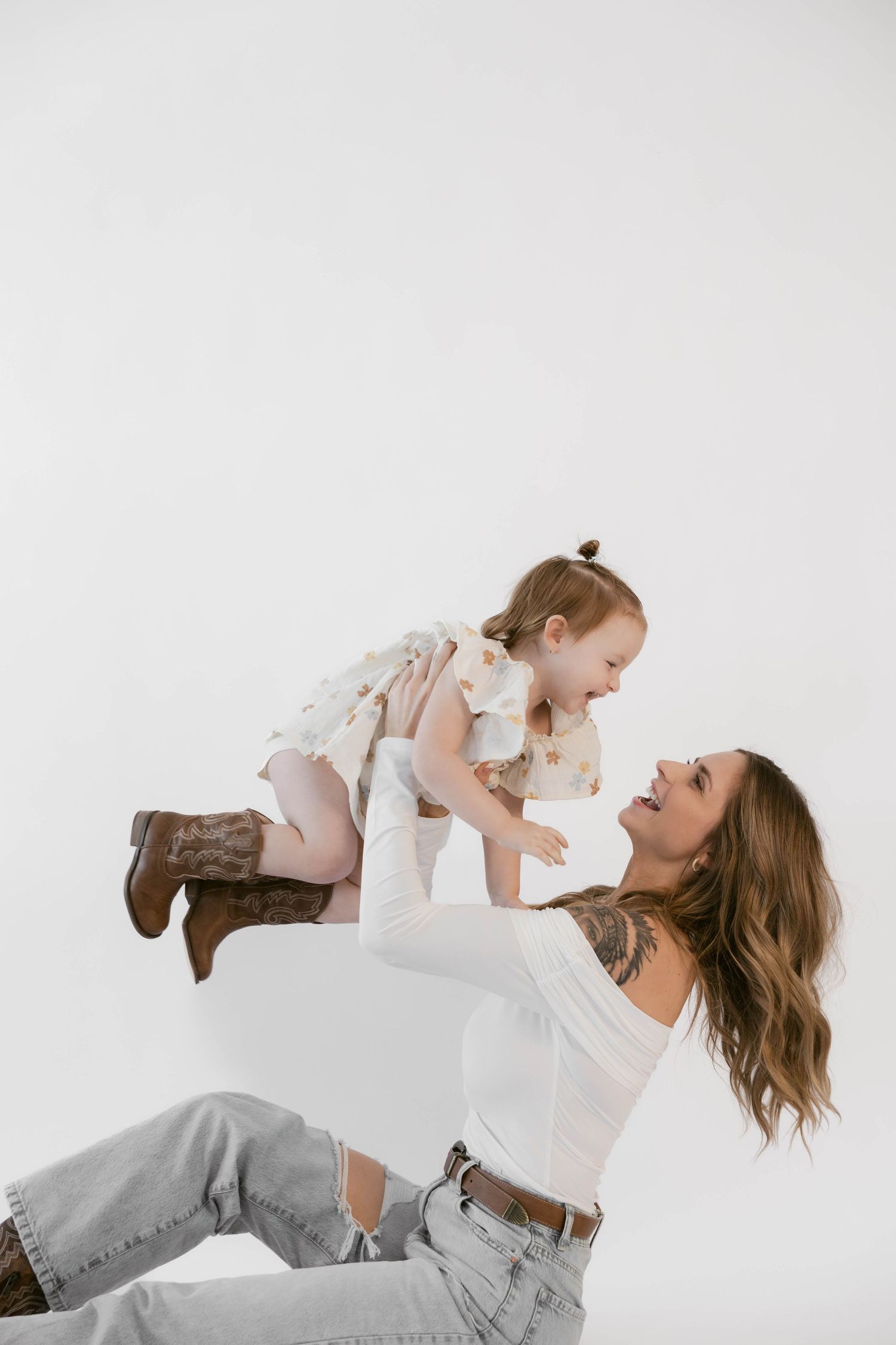 Playful studio portrait featuring western boots and casual denim styling.