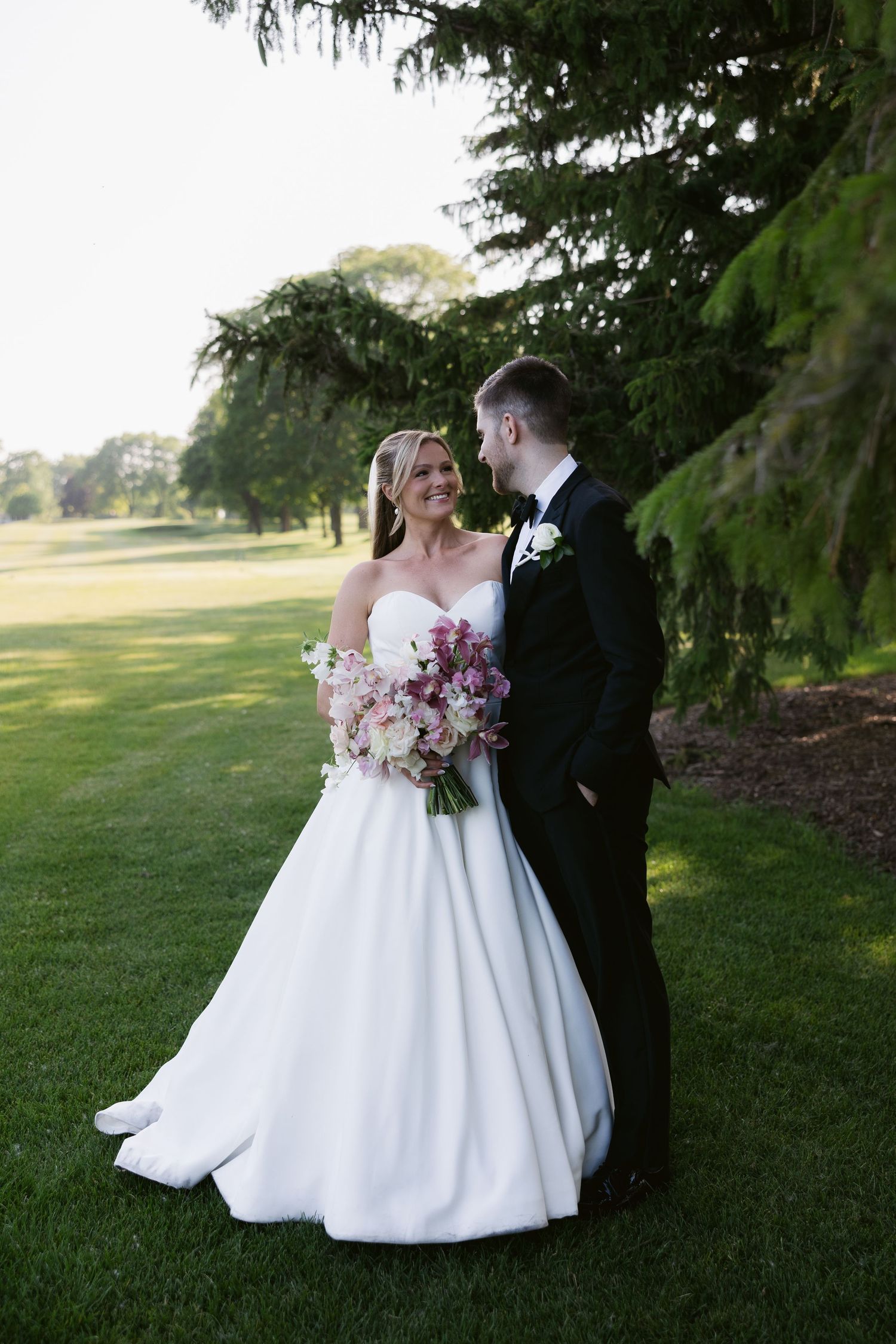 Romantic wedding photos taken on lush green lawn with elegant white ballgown.