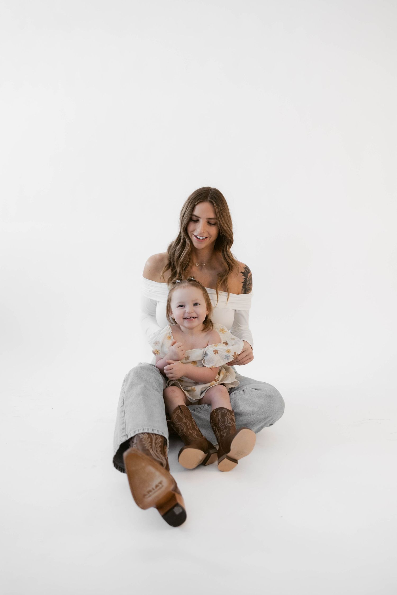 Playful candid moments captured between parent and child in minimalist white studio.