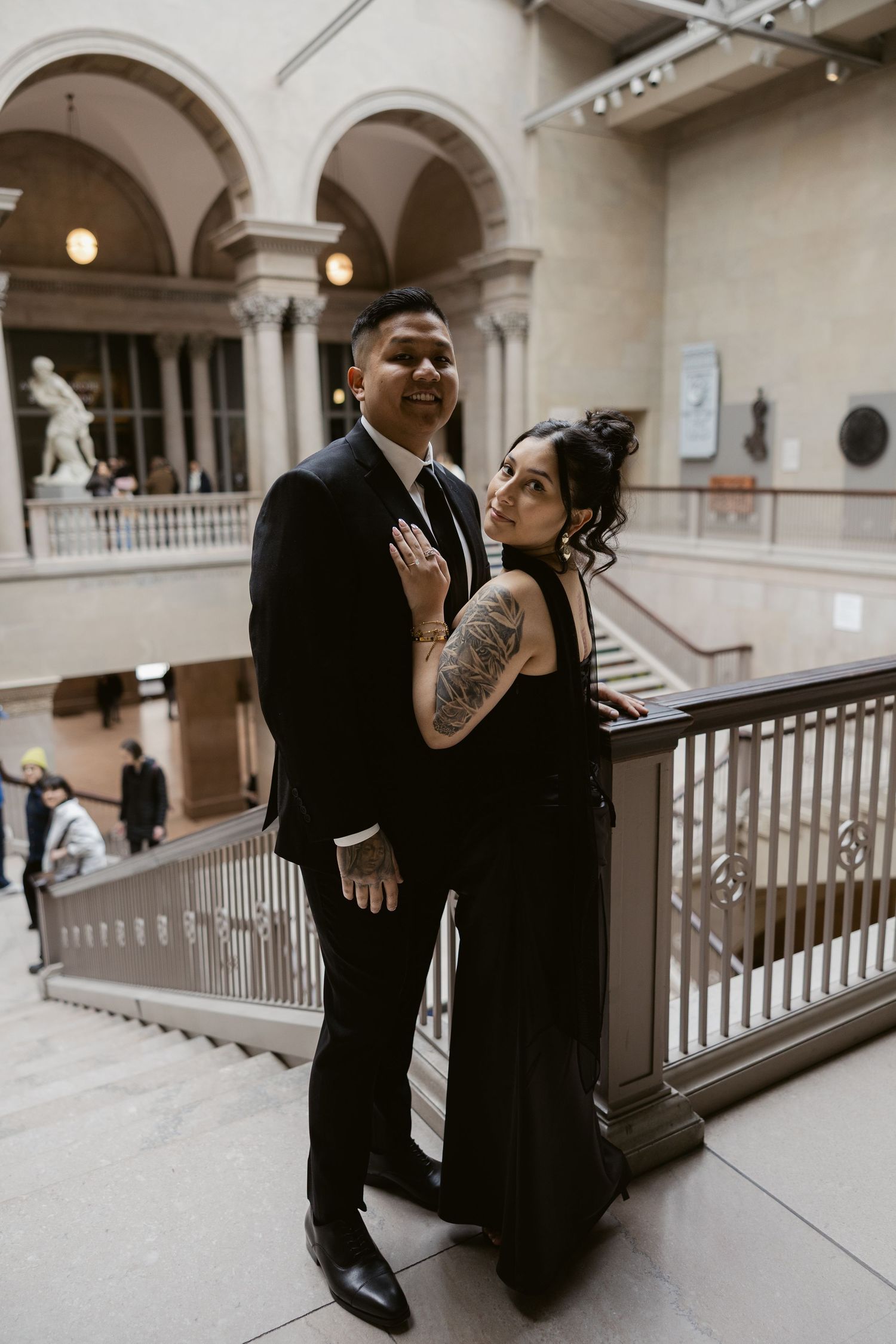 A couple shares romantic moments in an elegant museum hallway with classical architecture.