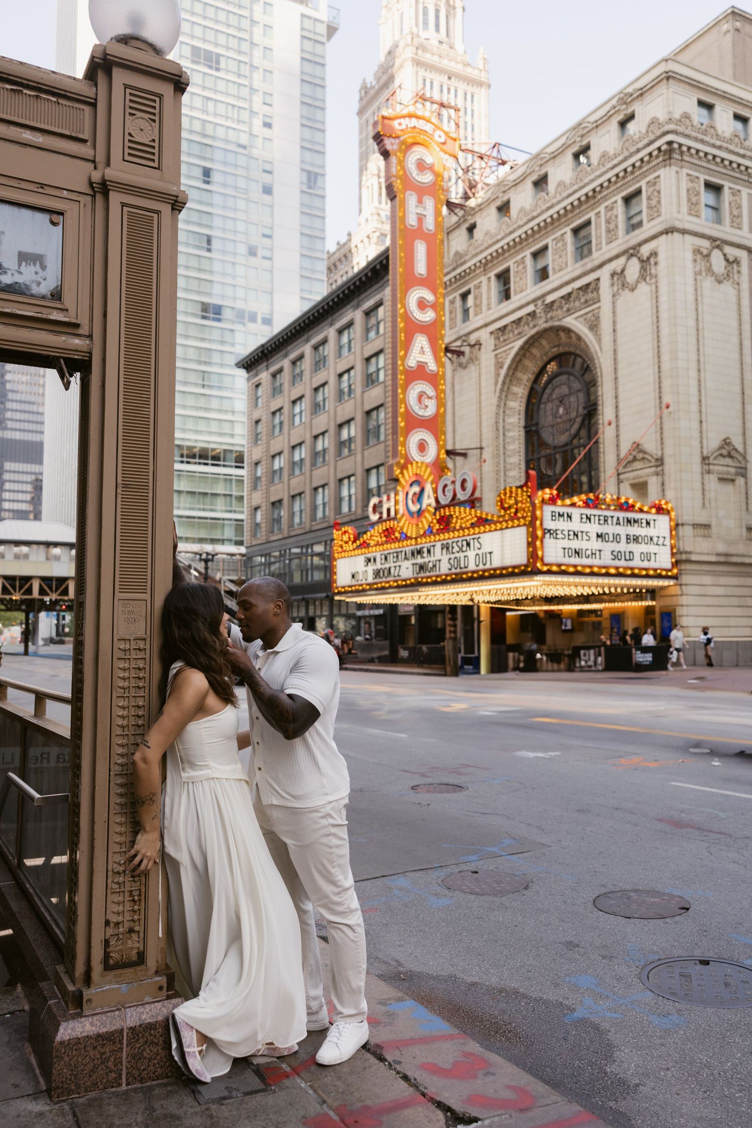 A couple in white poses outside the historic Chicago Theatre with its iconic illuminated marquee.