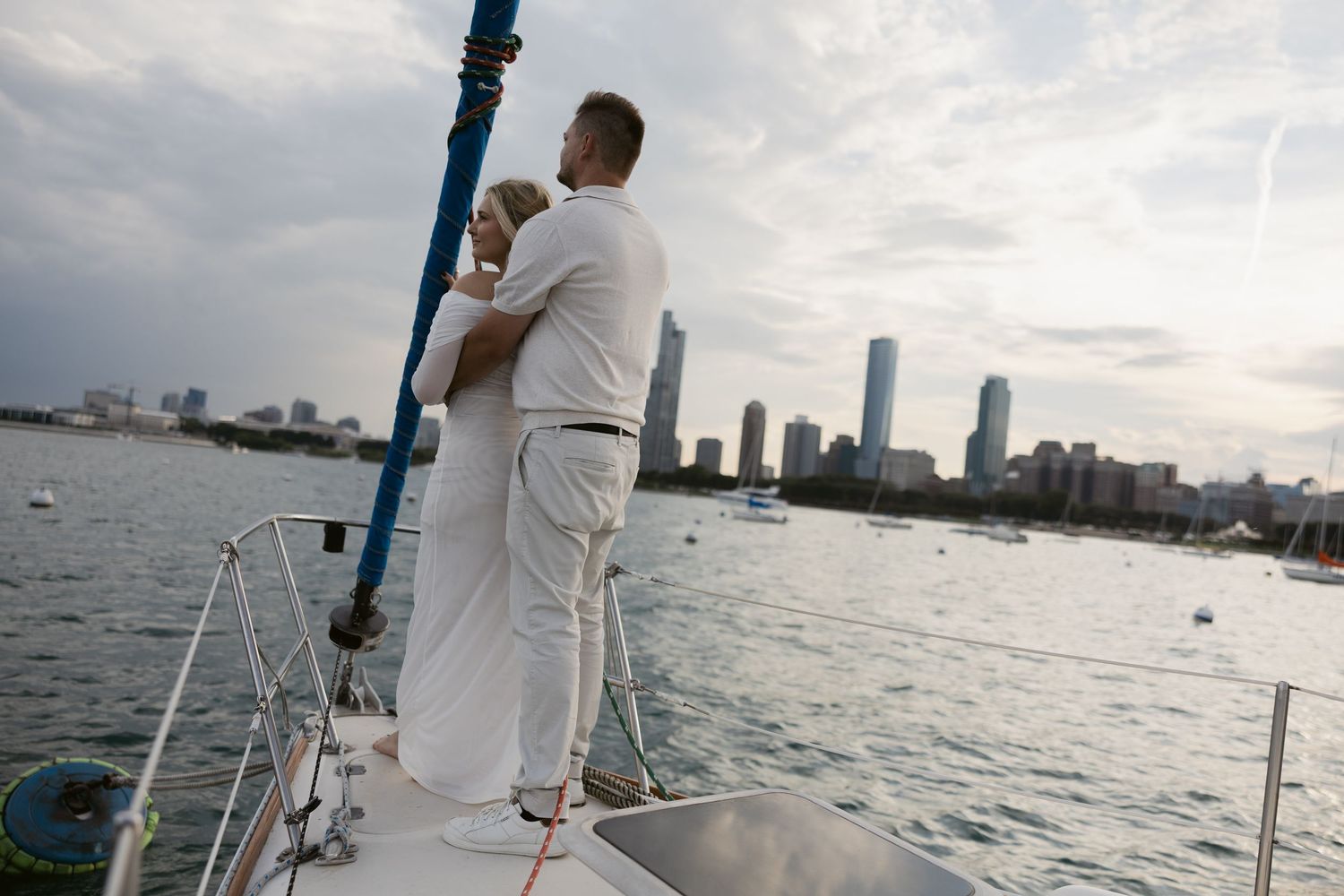 A yacht sails across Miami's waterfront with the city skyline visible in the background during sunset.