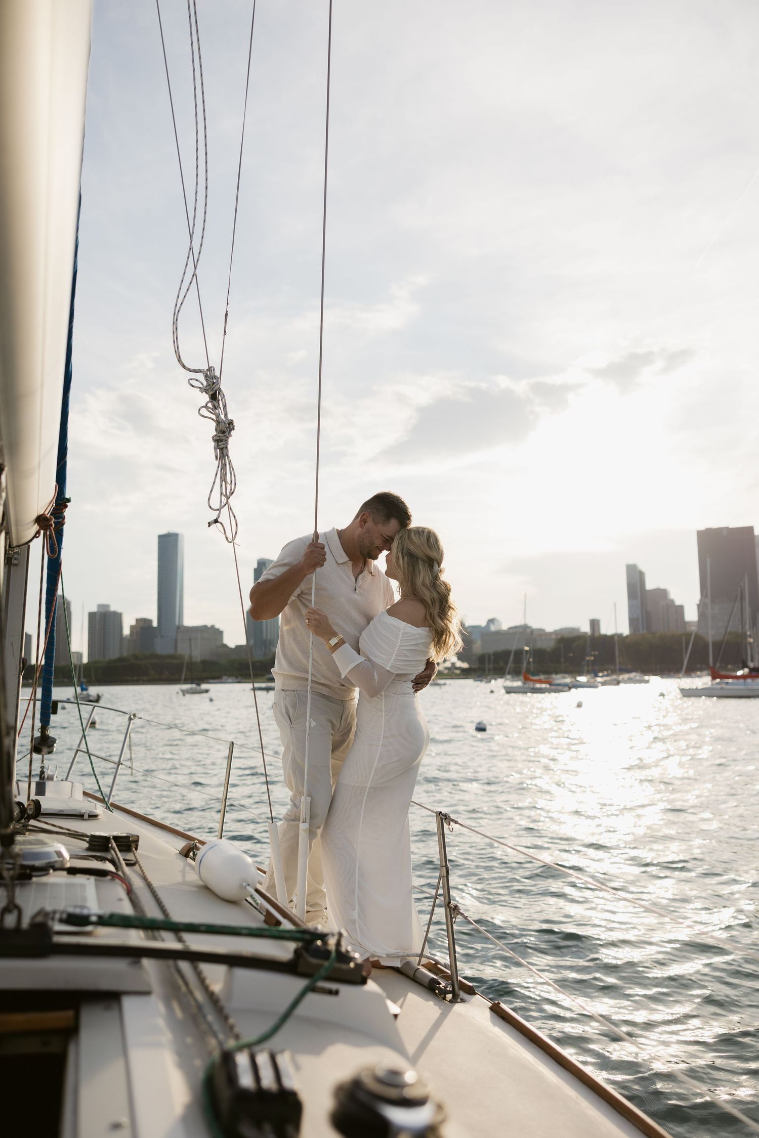 A couple shares a romantic moment on a sailboat with the Miami skyline visible across the water at sunset.
