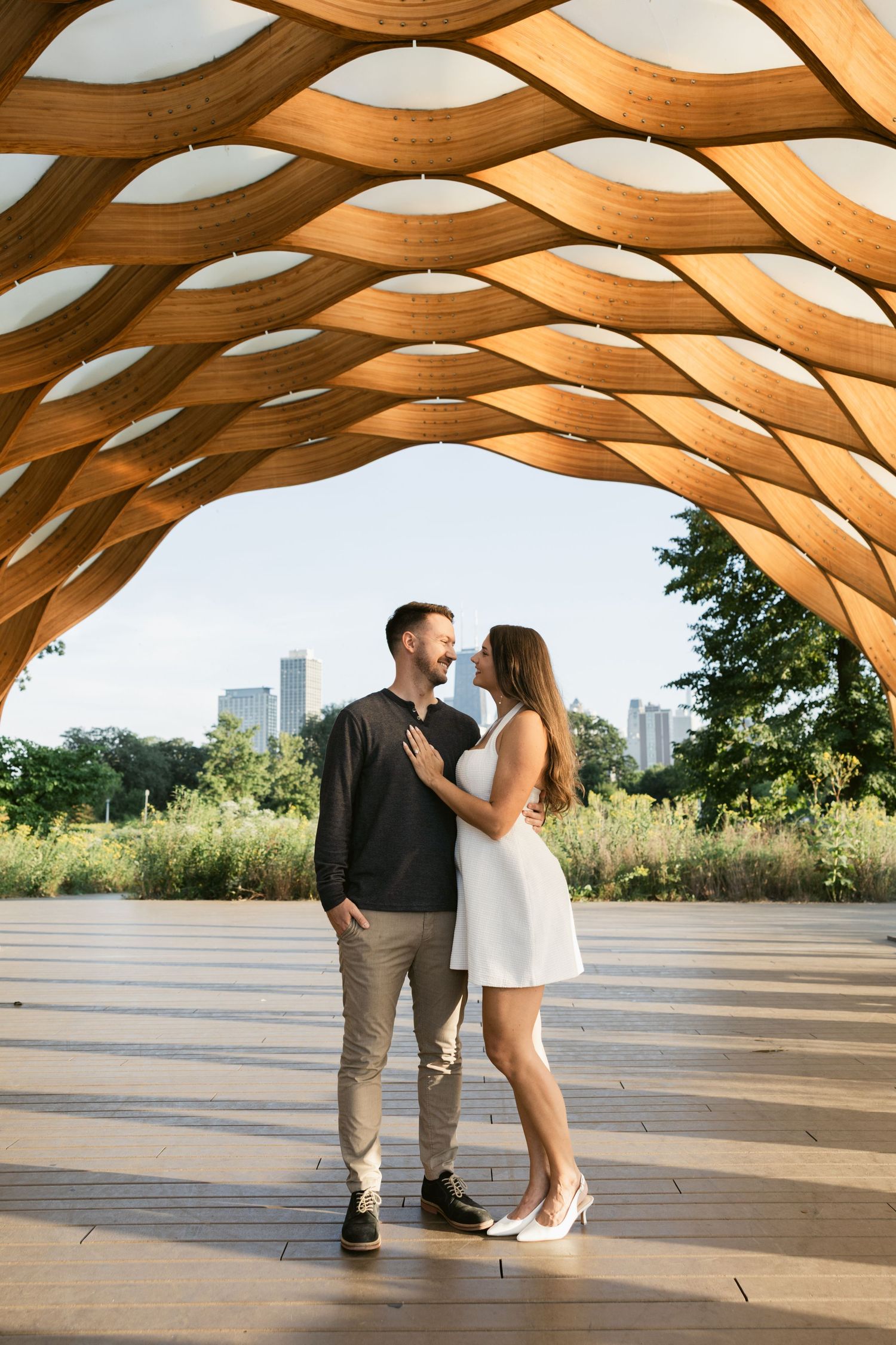 Couple sharing romantic moments under a wooden pavilion with curved architectural details.