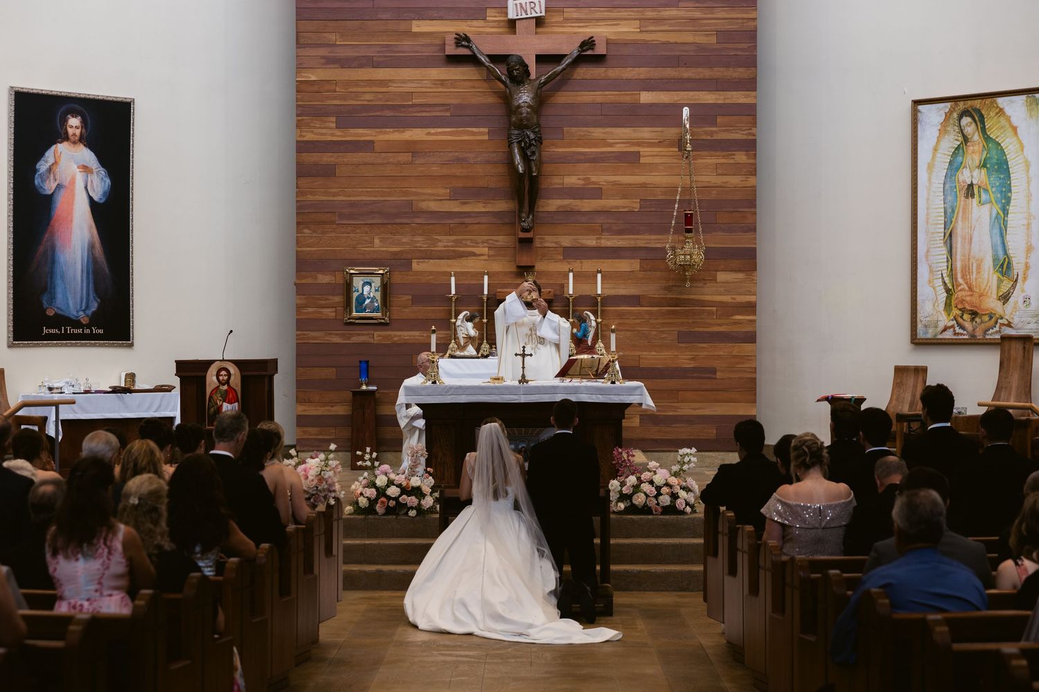 Church interior decorated for a wedding with wooden wall panels and religious artwork.
