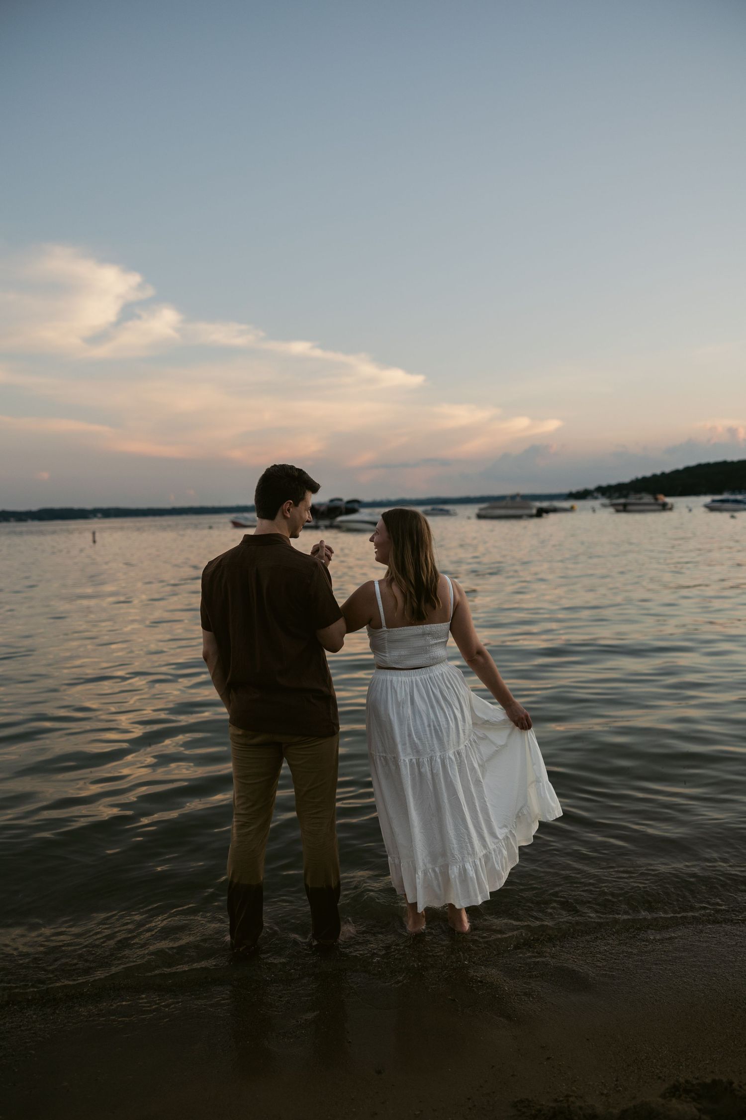 Silhouetted couple poses romantically against a sunset lake backdrop.