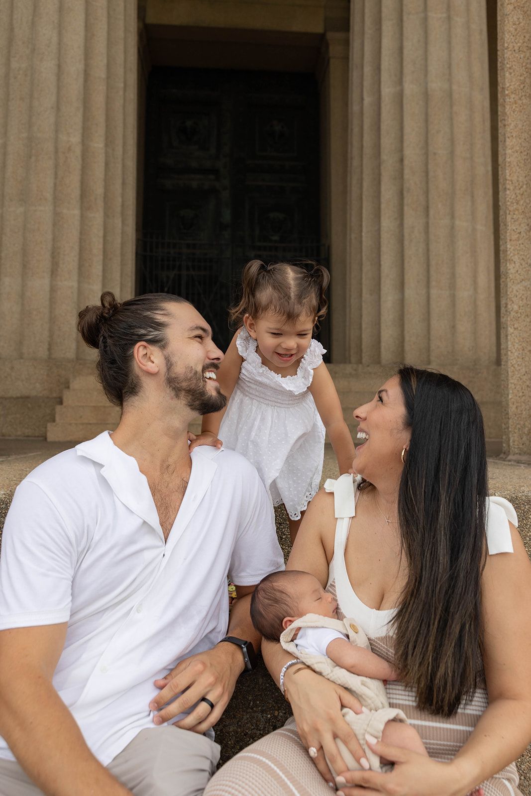 A joyful family moment captured on stone steps with parents and two young children.