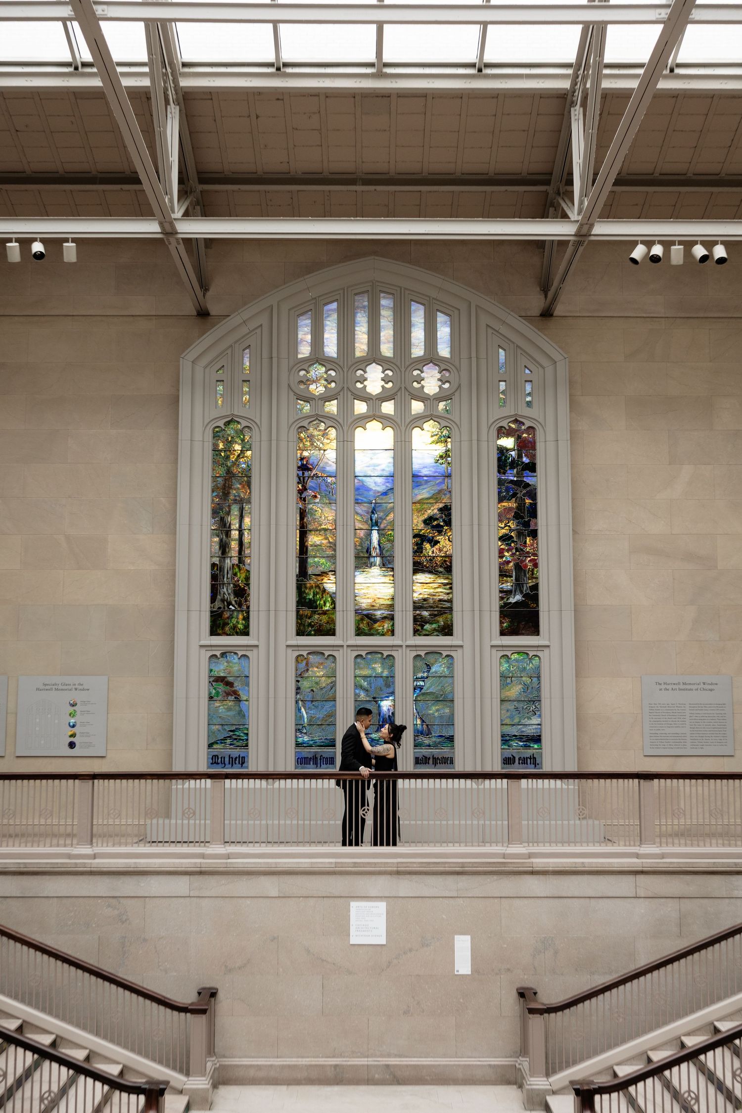 An elegant interior space with arched stained glass windows and stone staircase.