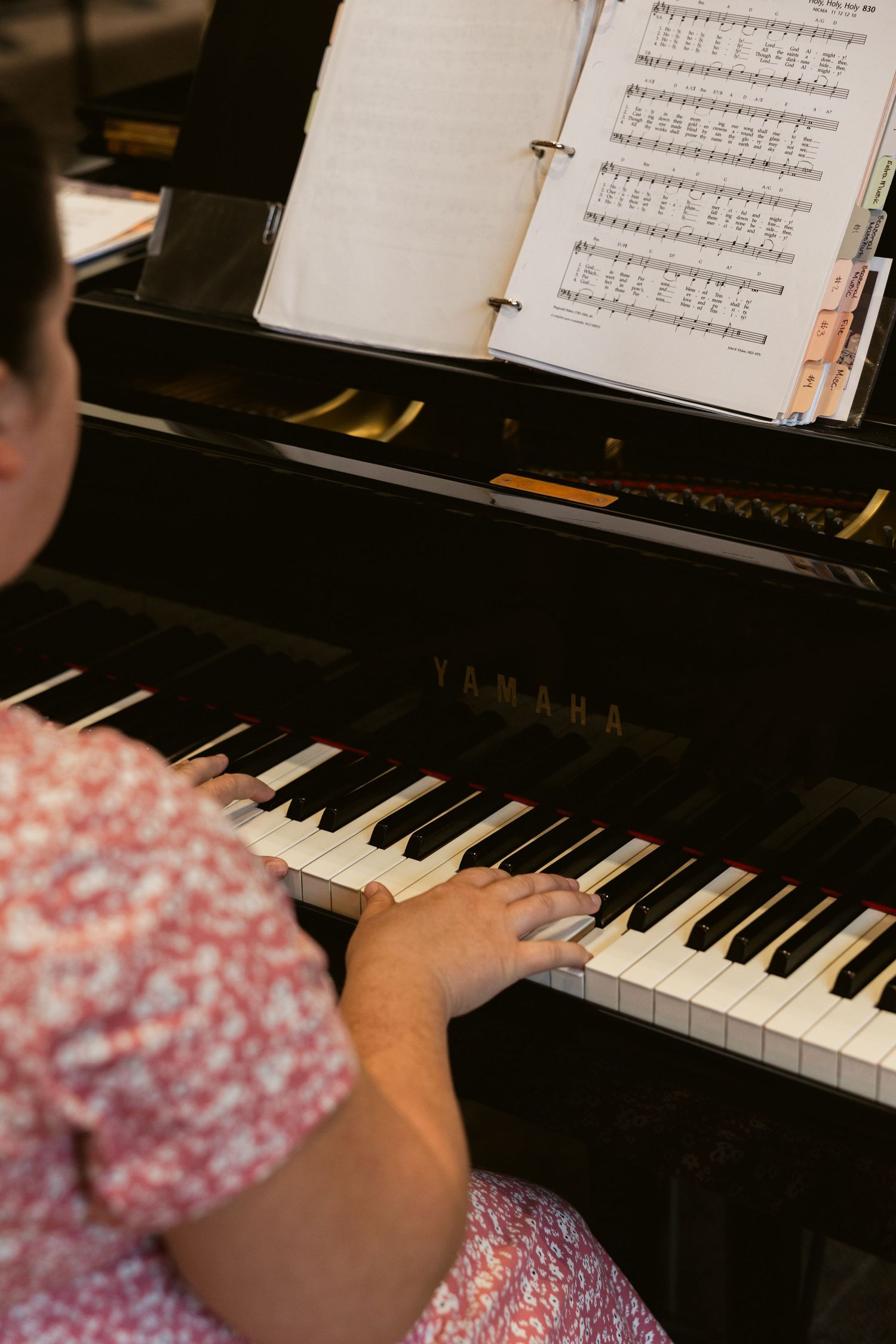 Close-up view of hands playing a Yamaha piano with sheet music visible.