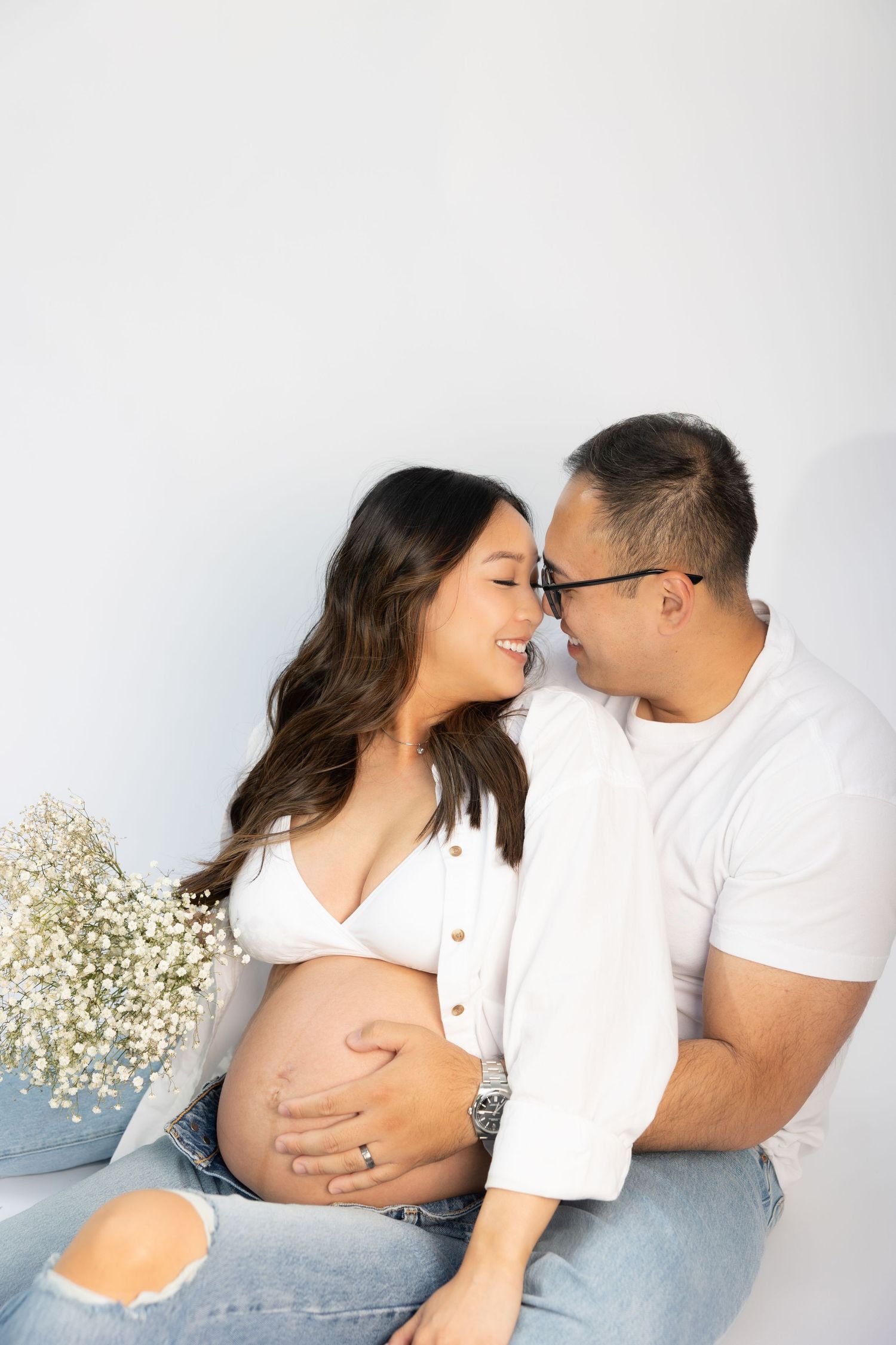 Intimate maternity photo of couple sharing tender moment with baby's breath flowers.