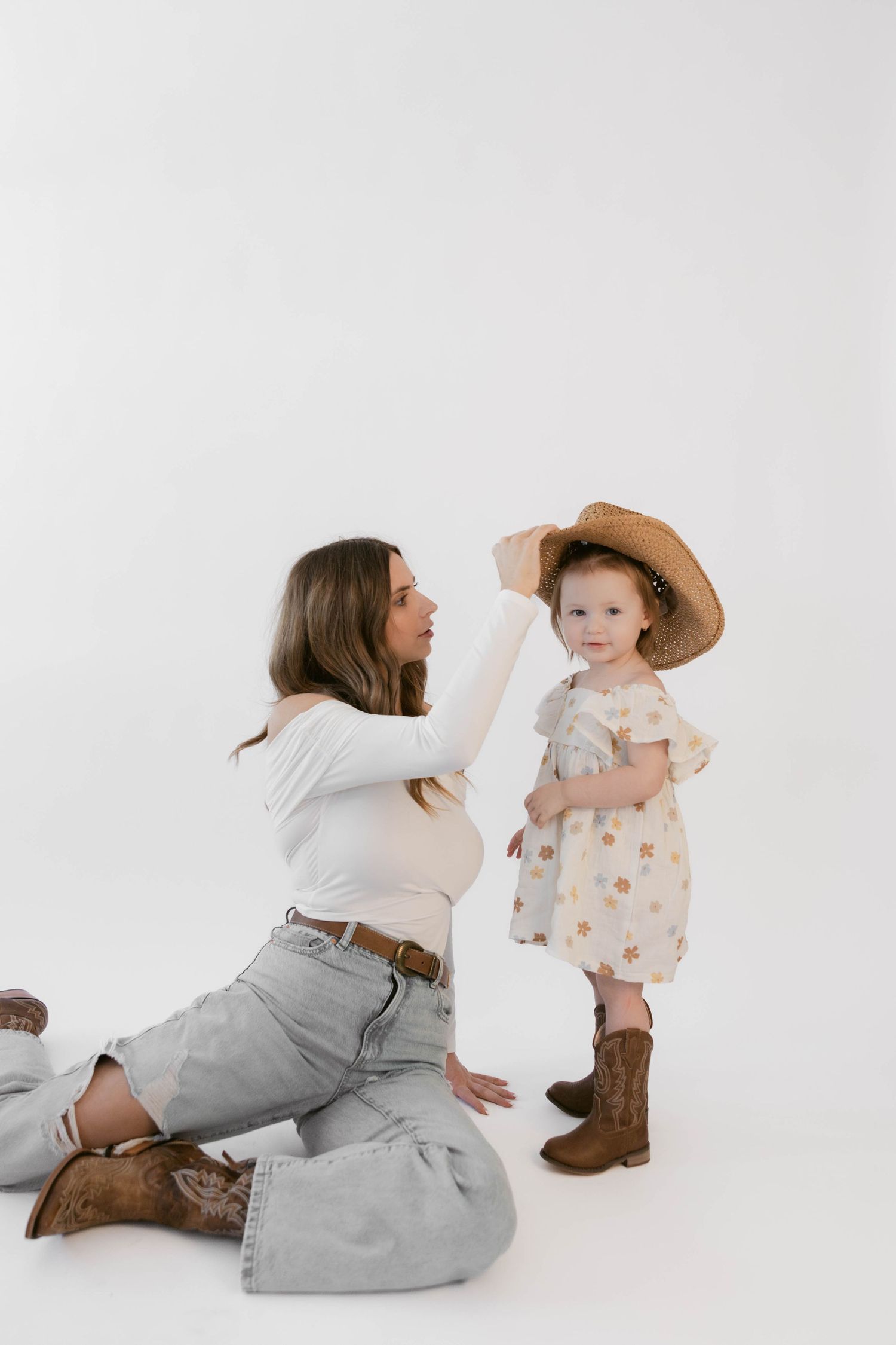 Candid studio shots capture playful interaction with straw hat and brown boots.