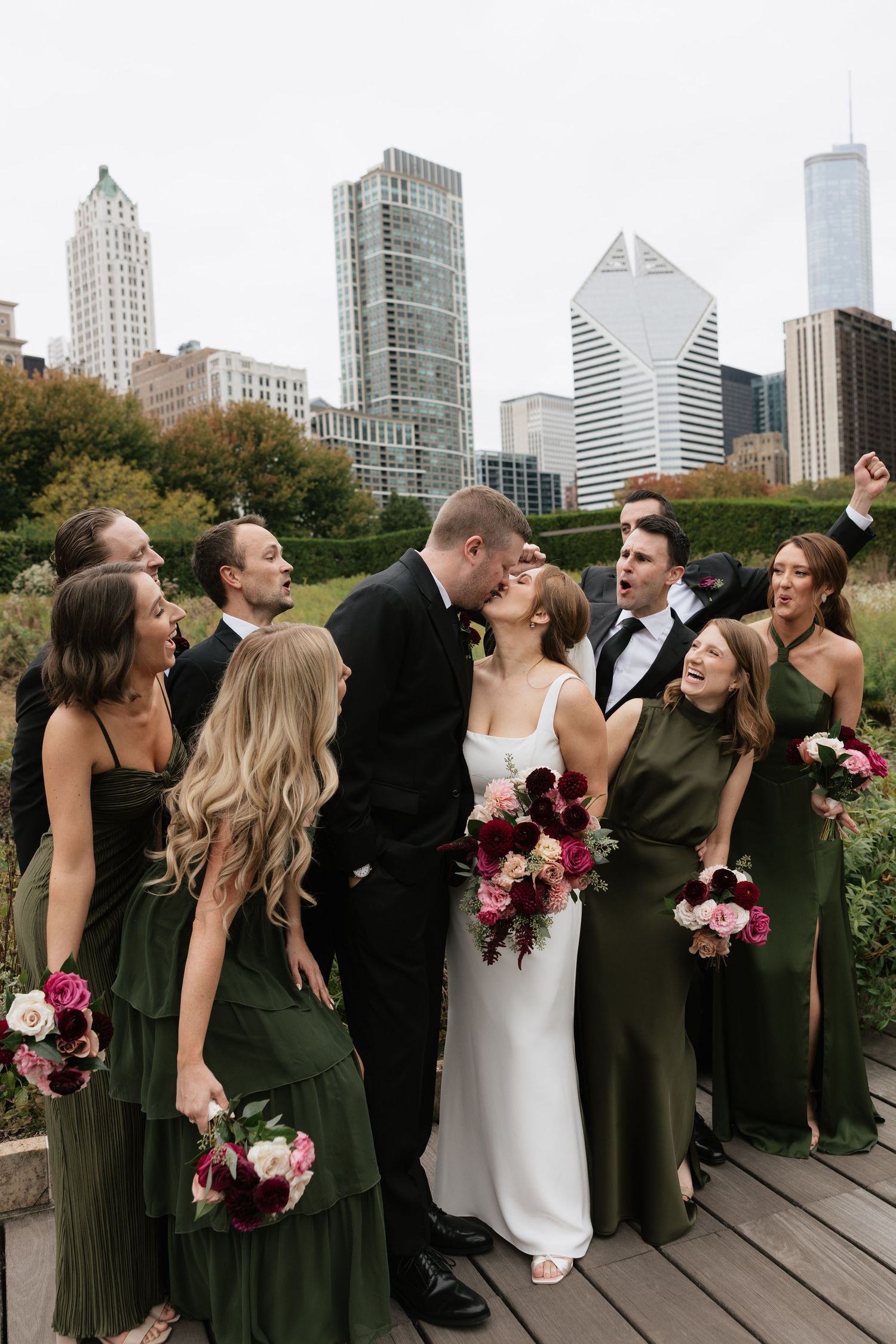 Wedding party poses playfully on a rooftop deck with Chicago skyline in the background.
