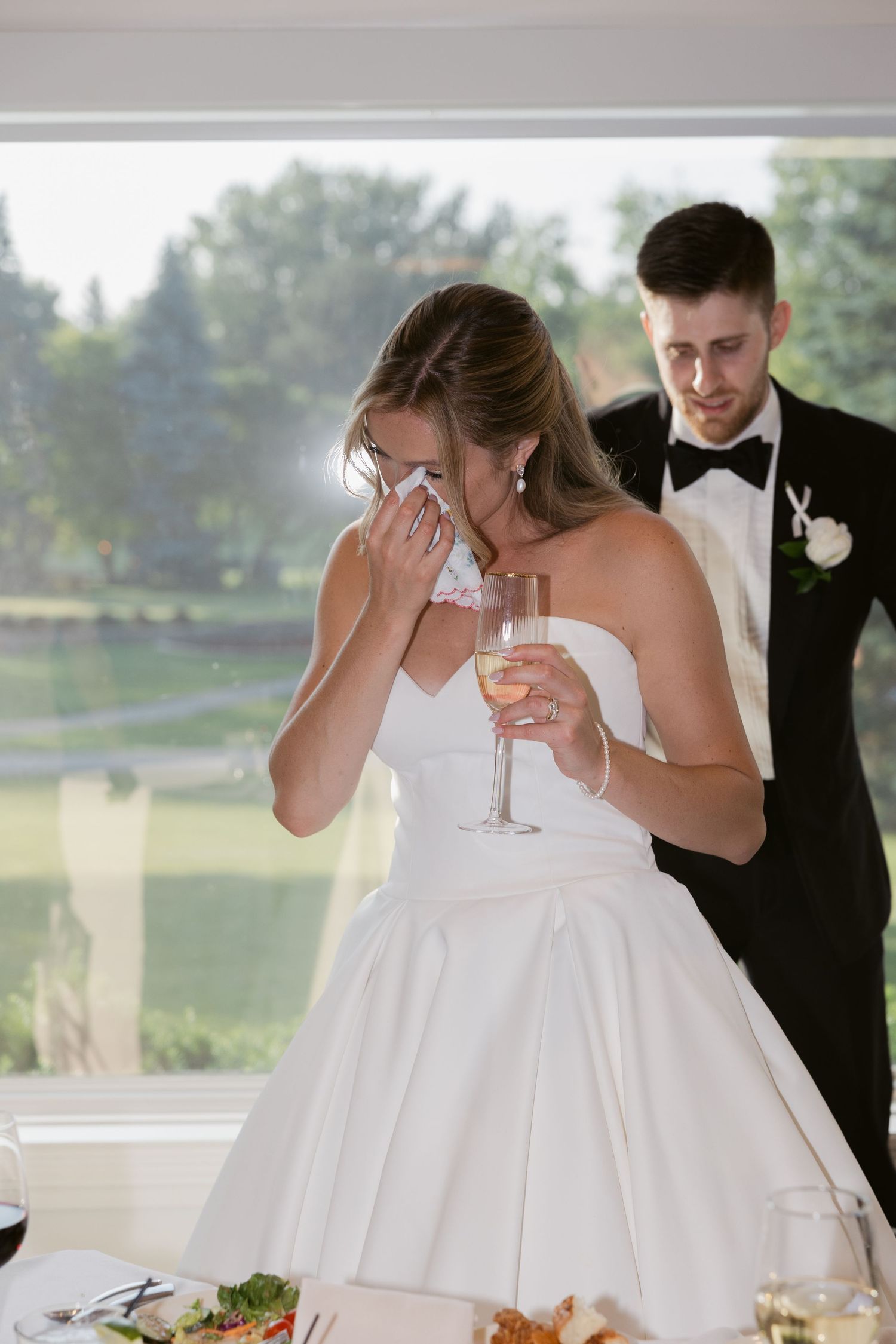 Wedding guests in formal attire sharing emotional moments and embracing during reception festivities.
