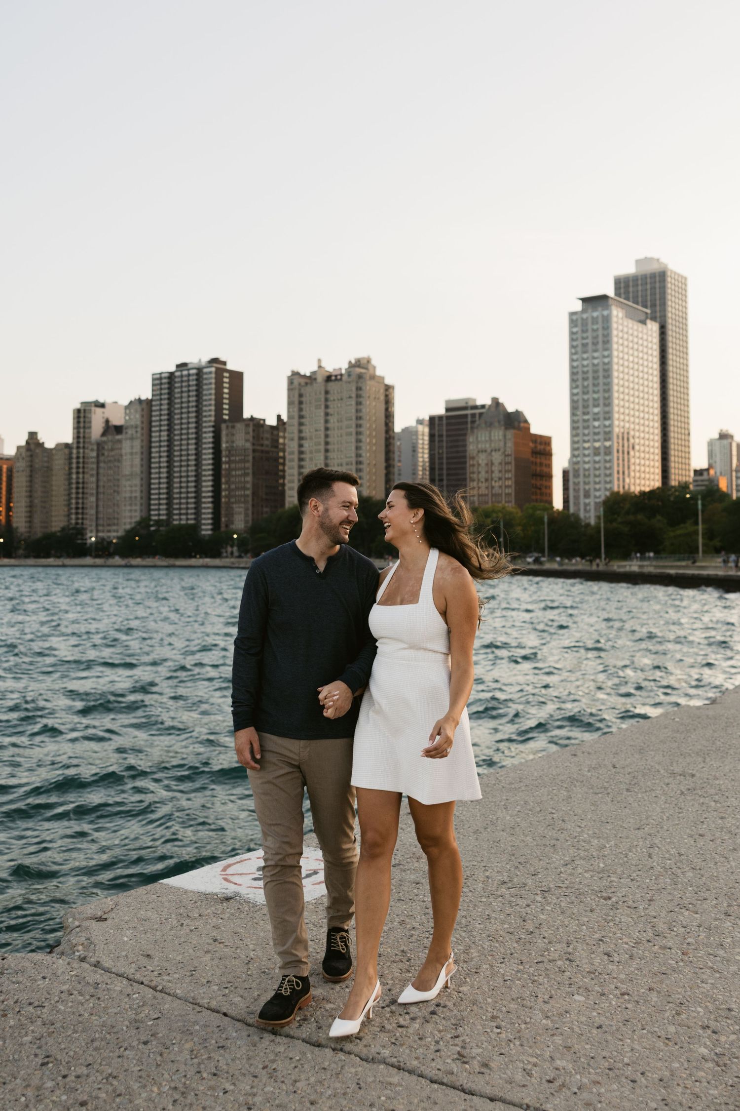 Couple walking together on North Avenue Beach with Chicago's downtown skyline visible.