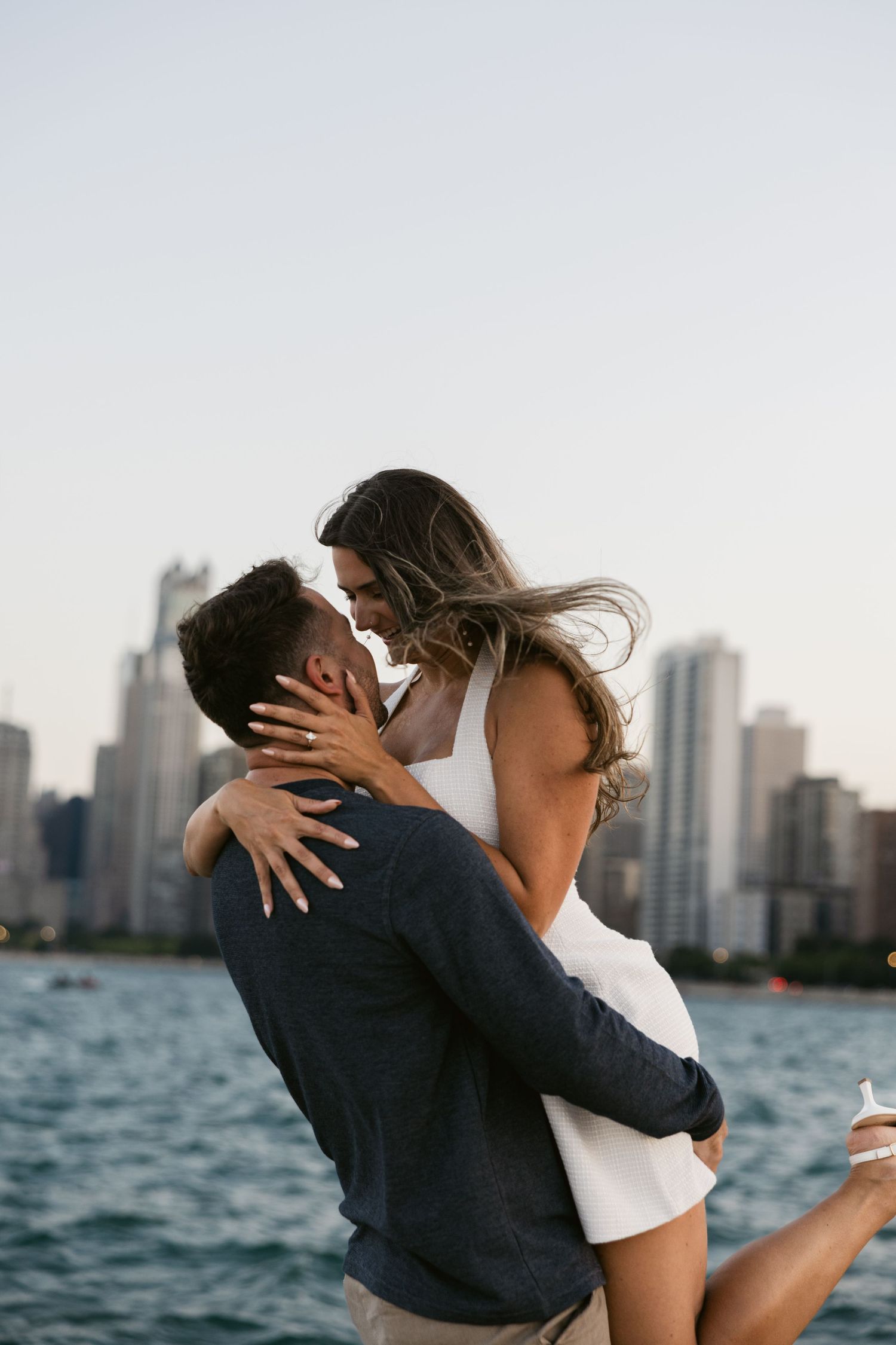 Embracing couple against Chicago skyline at waterfront during sunset.