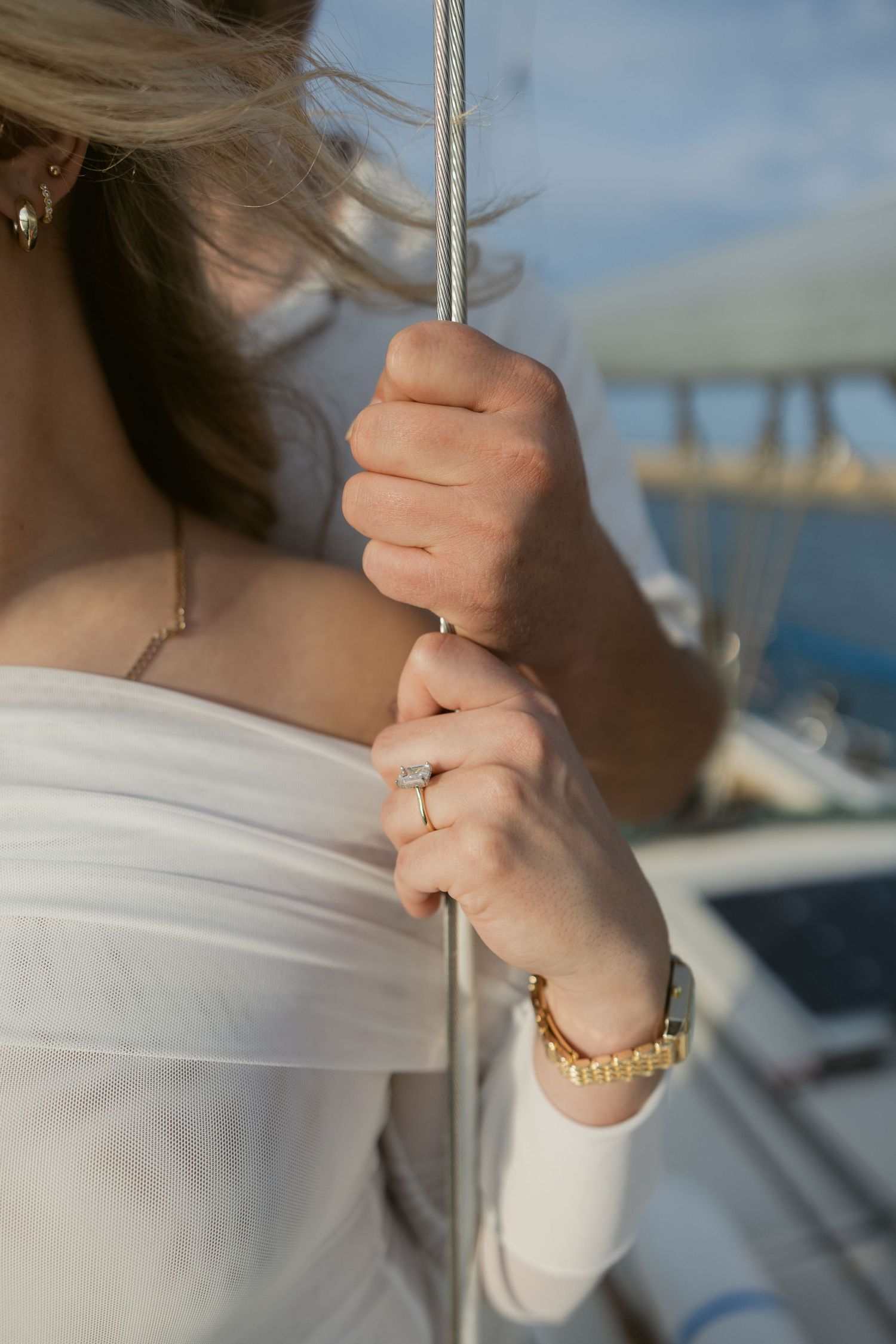 Detailed shots of hands and jewelry while holding sailing equipment on boat.